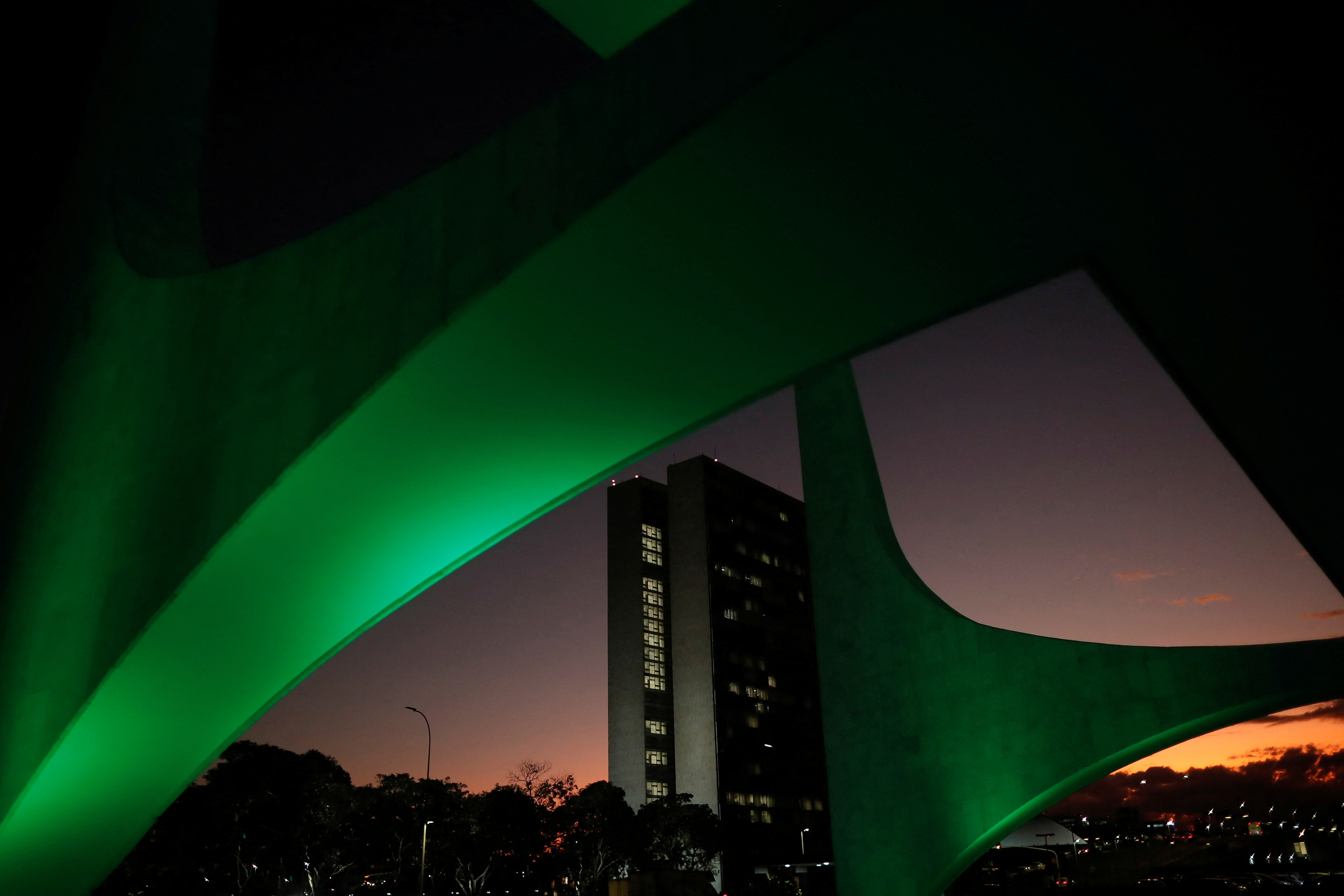 The national congress building is seen through architectural details of the Planalto Palace during sunrise in Brasilia