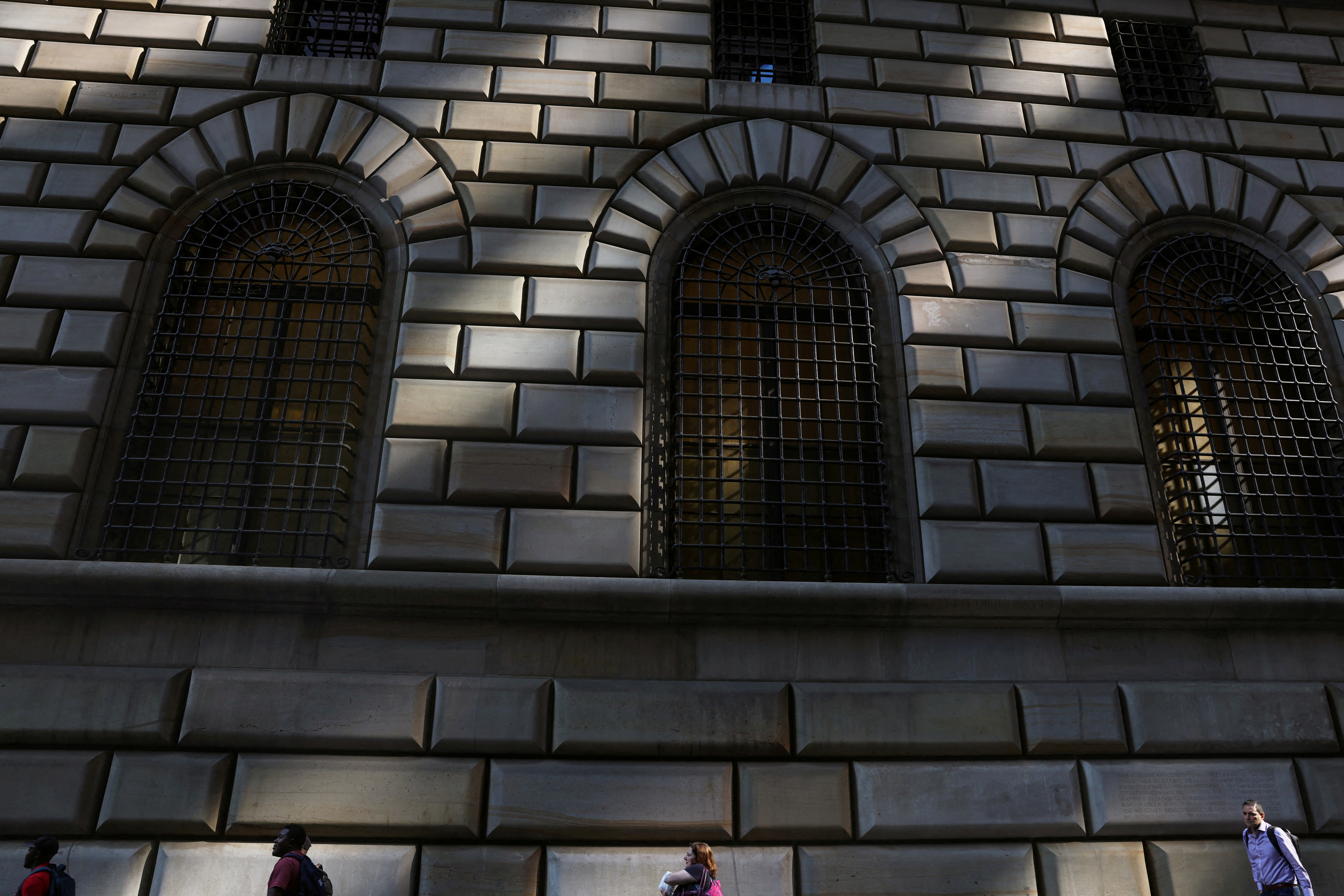 People walk by the Federal Reserve Bank of New York in the financial district of New York City