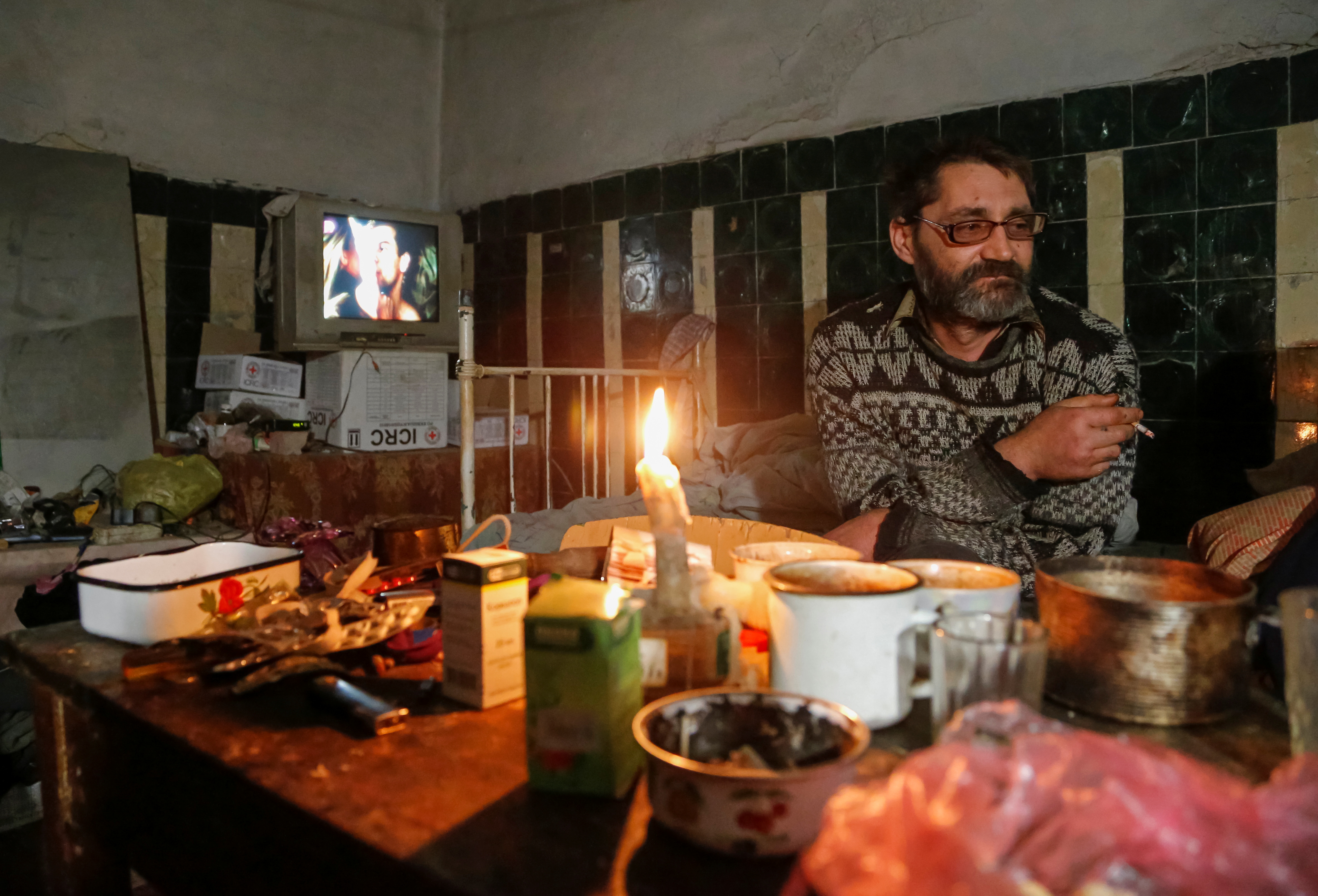 Local resident Alexander Studenikin, 44, smokes in a basement of a school building where he lives after his house was damaged by shelling, in the rebel-controlled town of Horlivka (Gorlovka) near Donetsk, Ukraine, November 24, 2021. Picture taken November 24, 2021.  REUTERS/Alexander Ermochenko