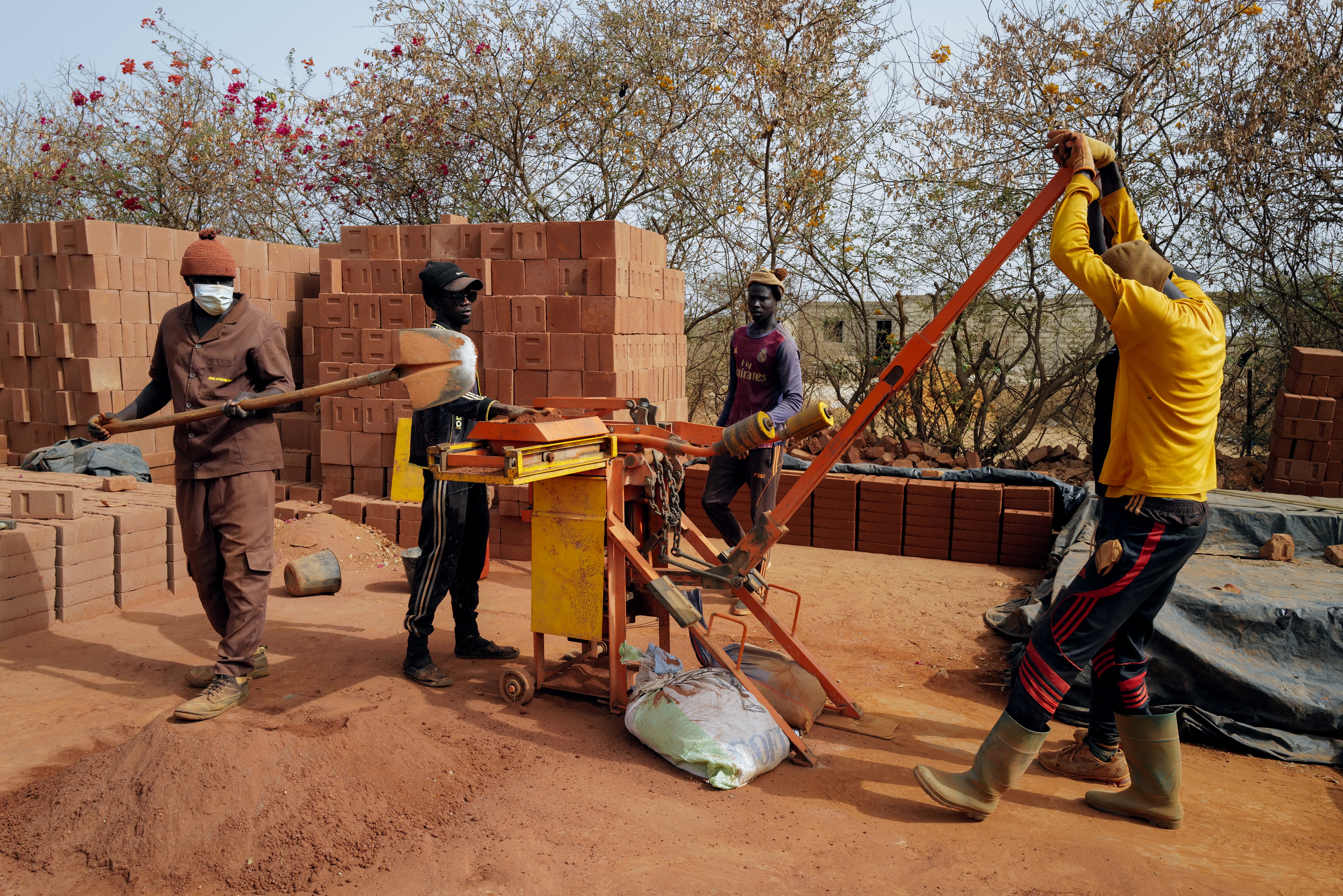 Workers make bricks with manual press at the Elementerre factory in Mbour
