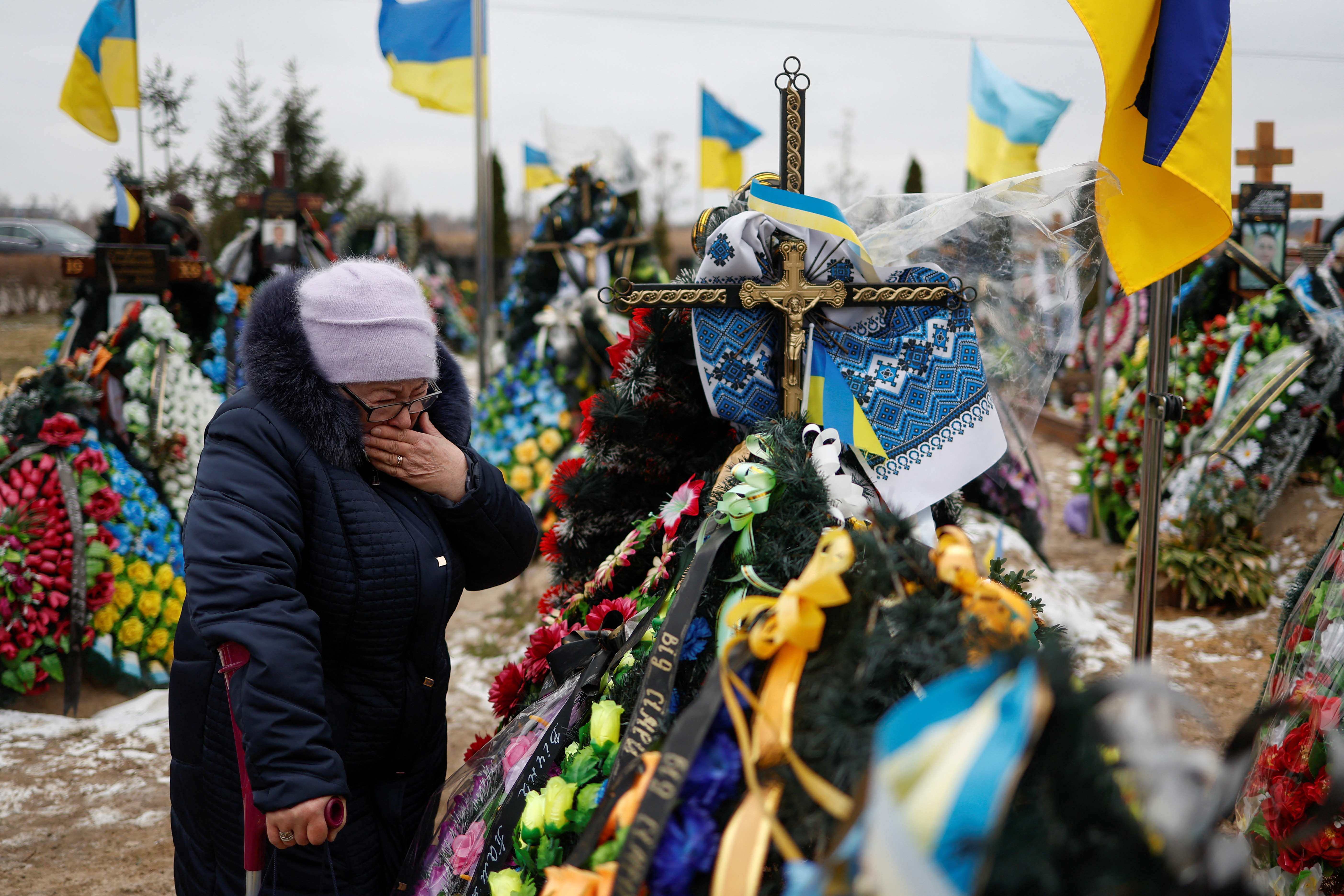 People visit graves of their relatives, on a day of the first anniversary of Russia's attack on Ukraine, in Bucha