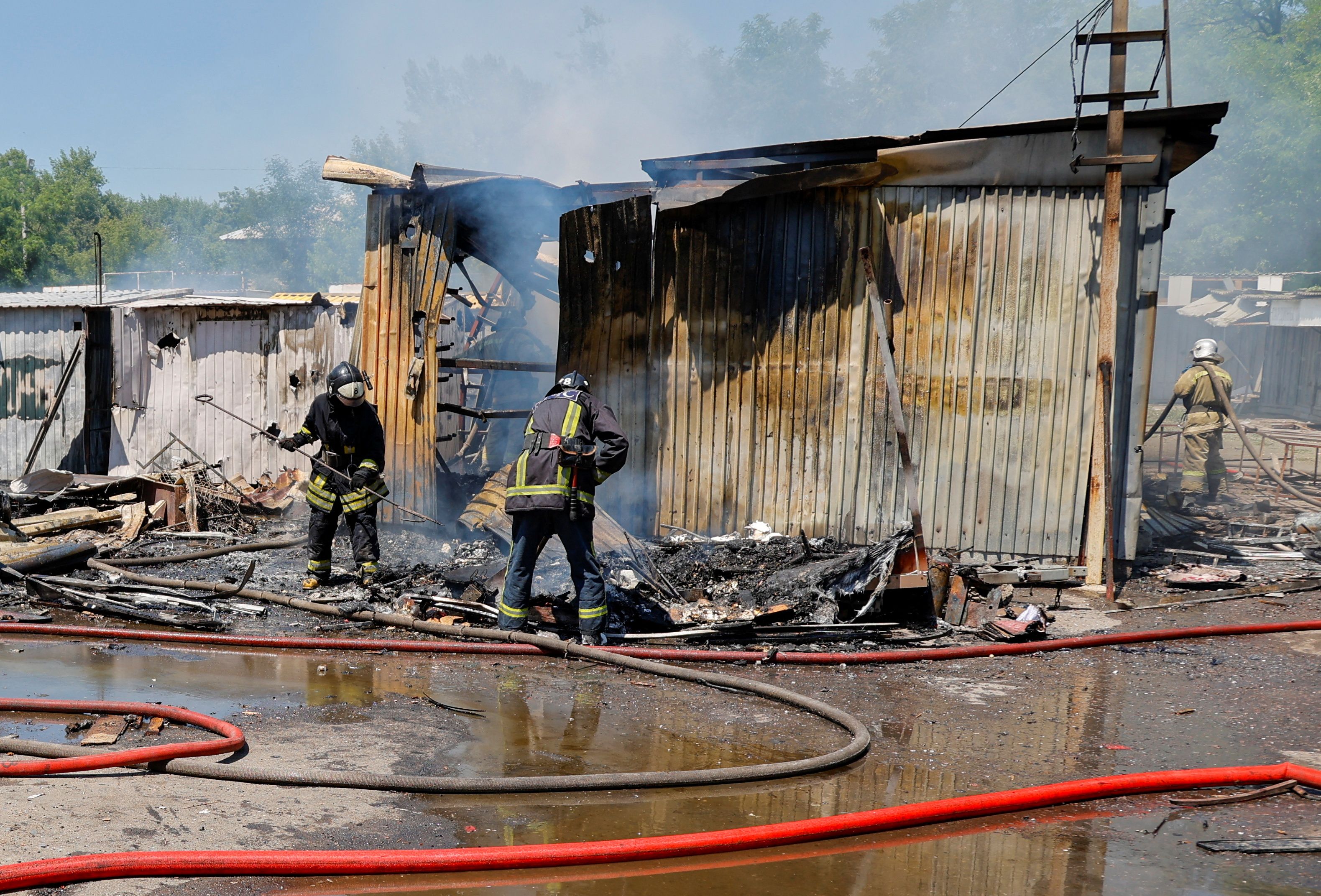 Firefighters extinguish a fire following recent shelling at a market in Donetsk