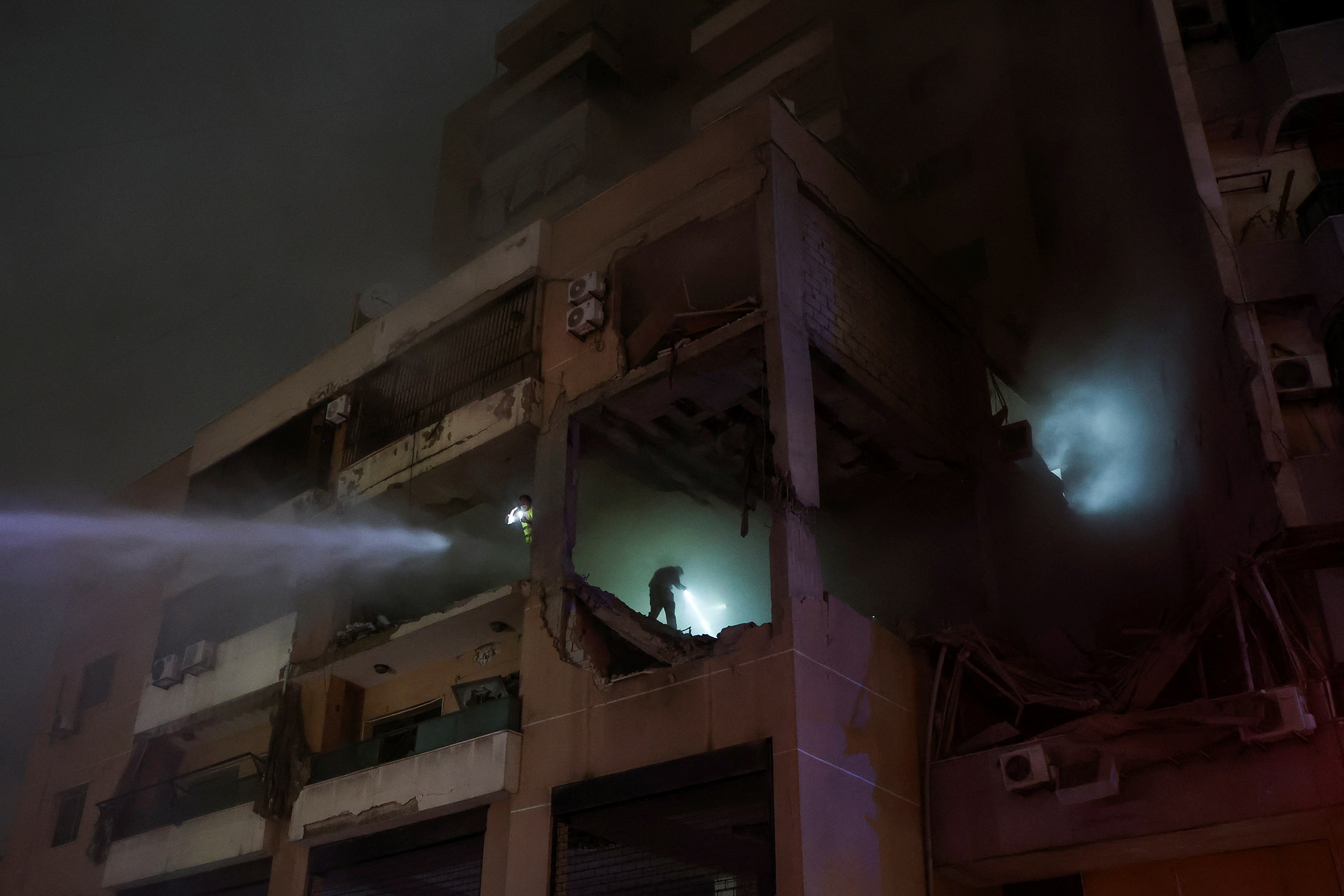 Water is sprayed on a damaged building at the site of an explosion, in what security sources say is an Israeli drone strike, in the Beirut suburb of Dahiyeh