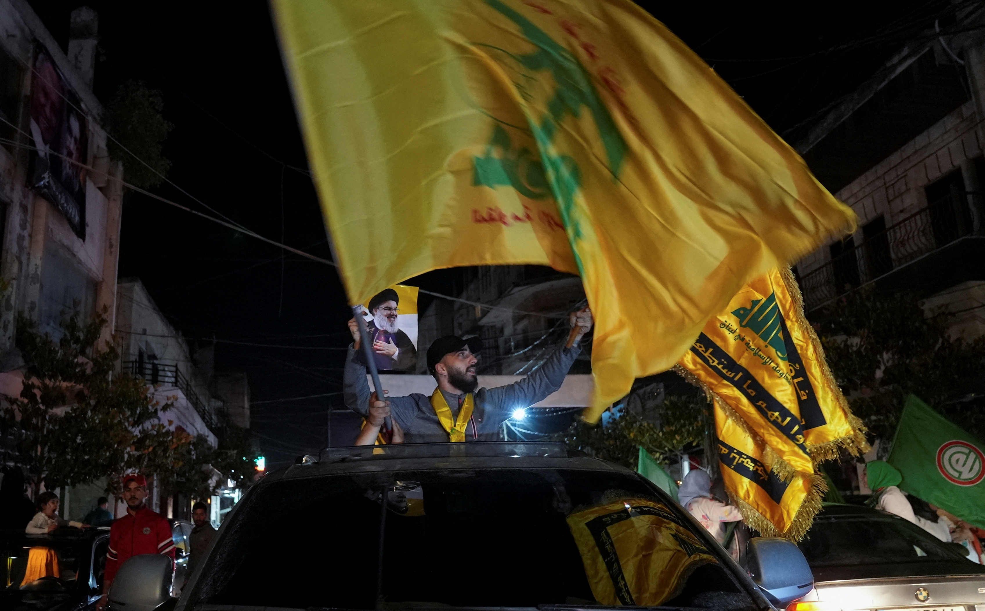 Supporters of Lebanon's Hezbollah leader carry flags while riding in a convoy, in Nabatiyeh