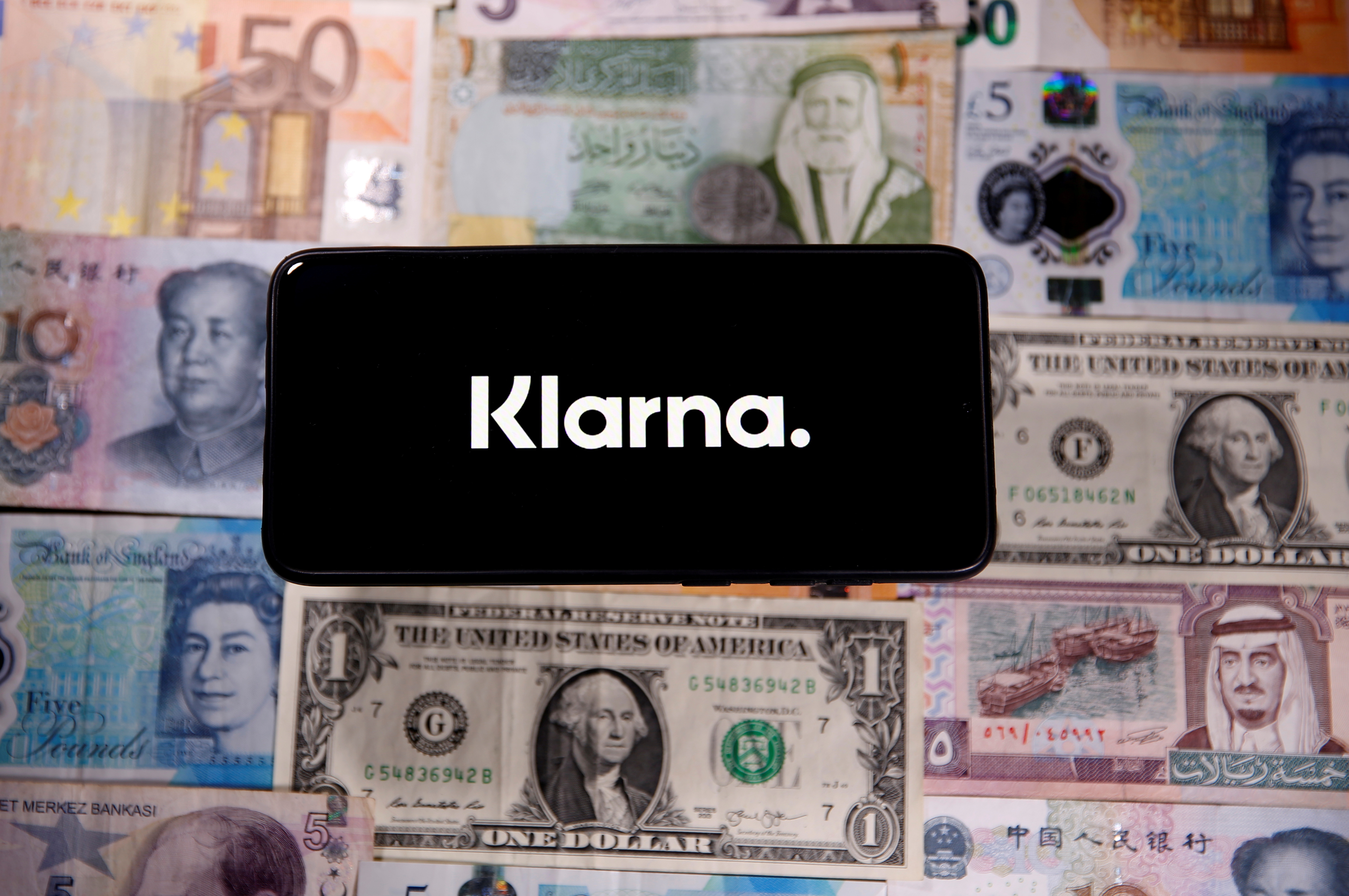 A smartphone displays a Klarna logo on top of banknotes is in this illustration