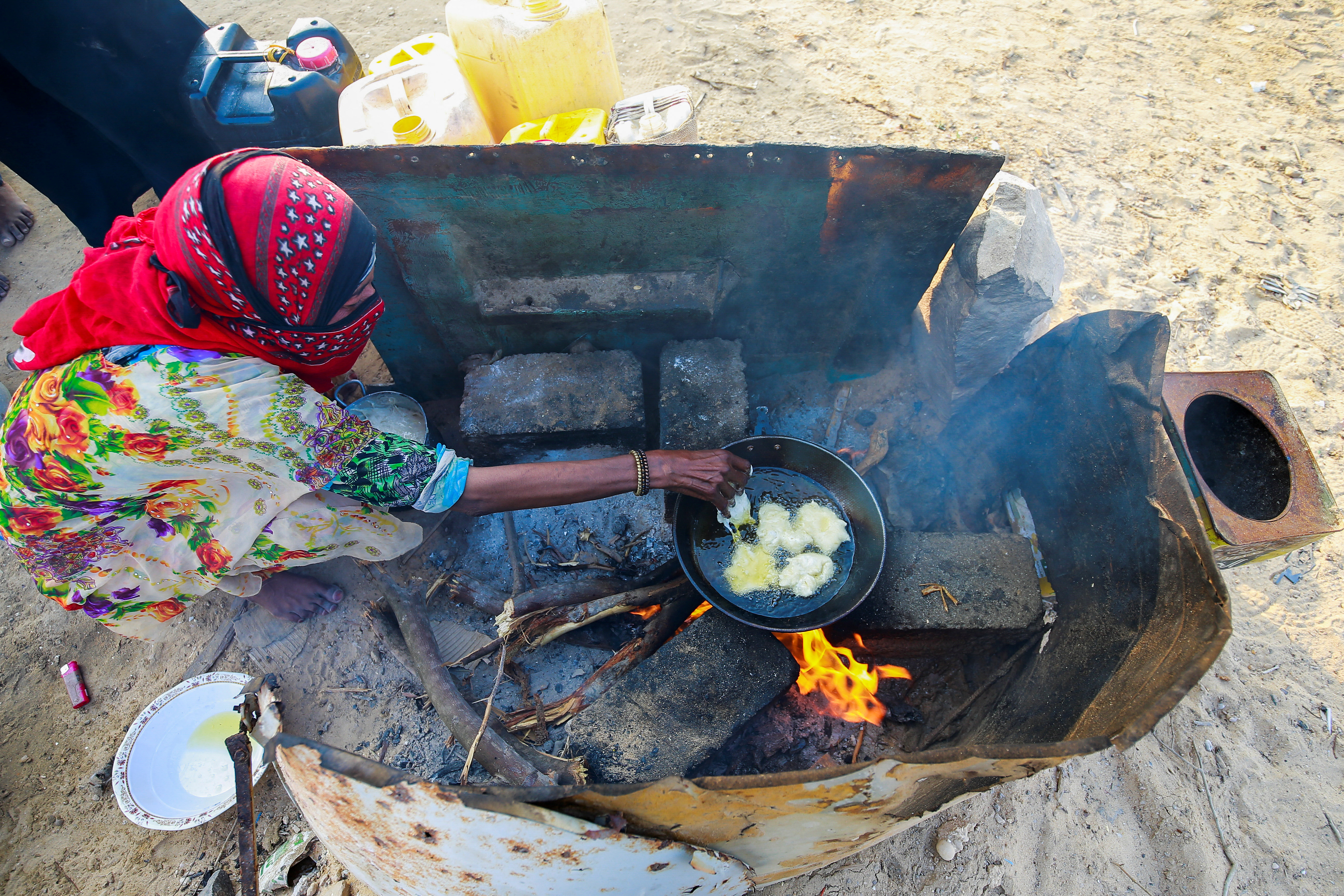 Woman cooks a meal at a camp for displaced people in al-Ghaidha