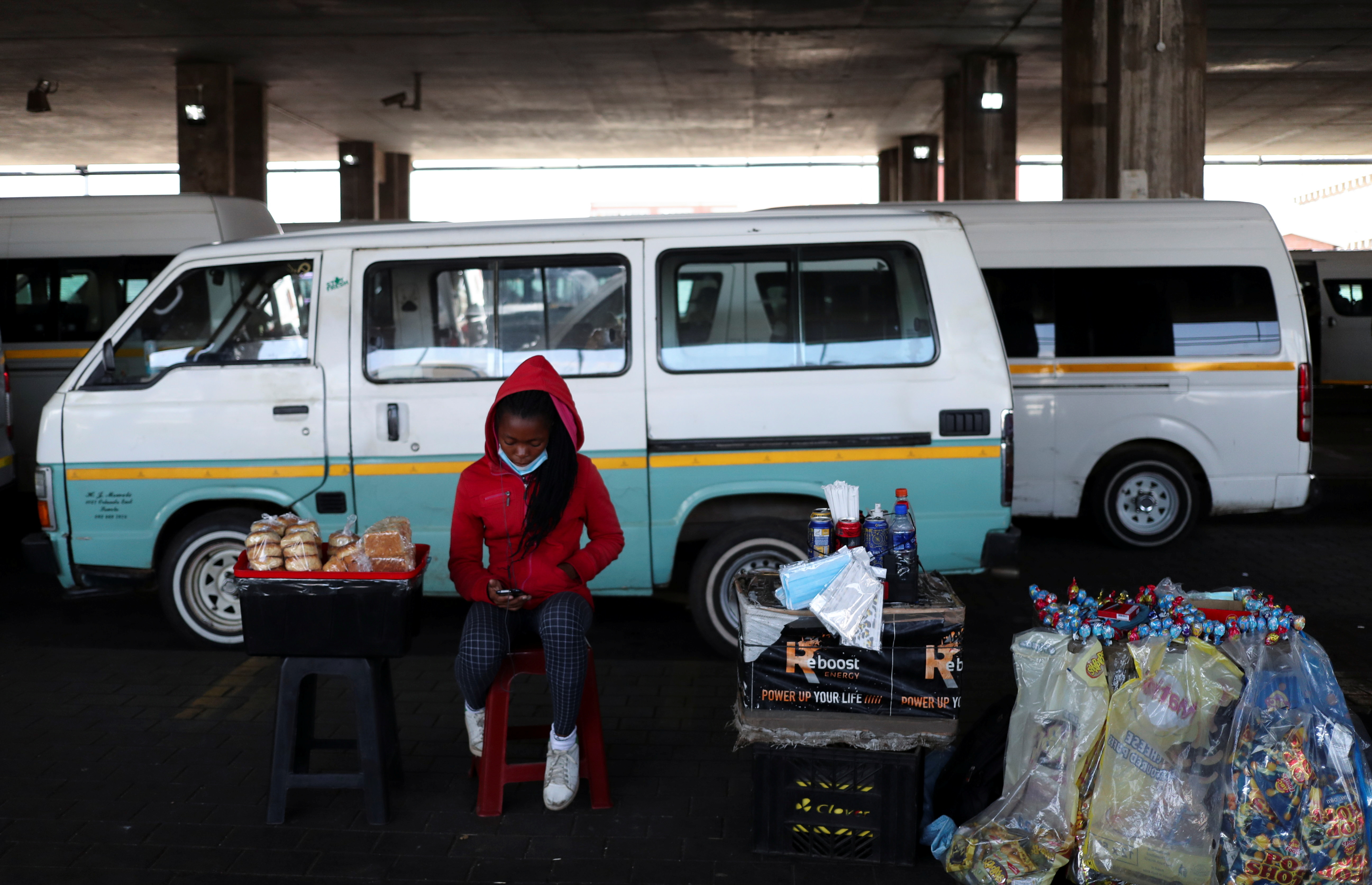 A street vendor looks at her mobile phone while sitting next to her goods following the announcement of a UK ban on flights from South Africa due to the detection of a new variant of coronavirus disease (COVID-19) in Soweto, South Africa, November 26, 2021. REUTERS / Siphiwe Sibeko
