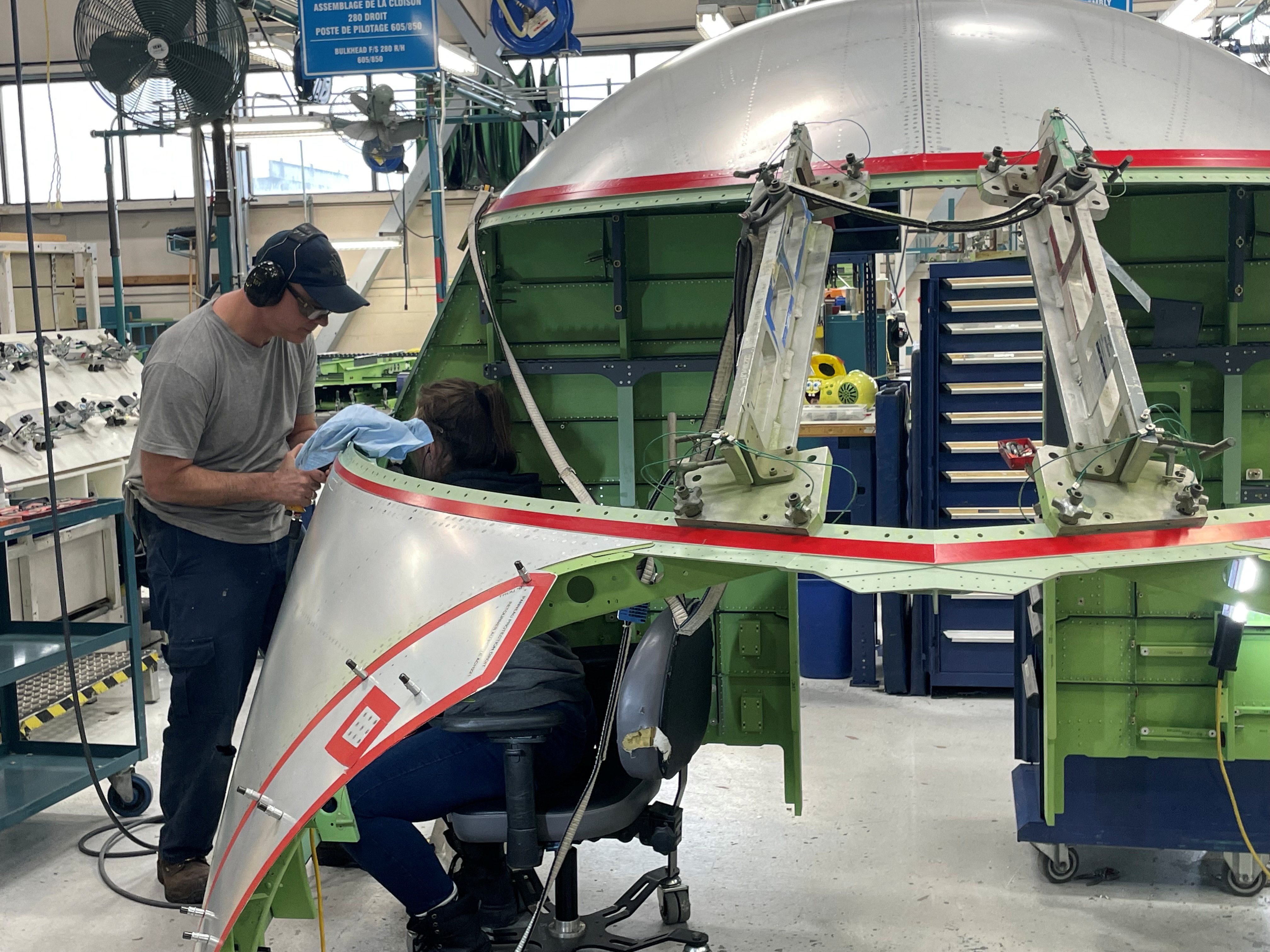 Bombardier workers install an aluminium skin panel on the cockpit of the Challenger 650 business jet, in Montreal