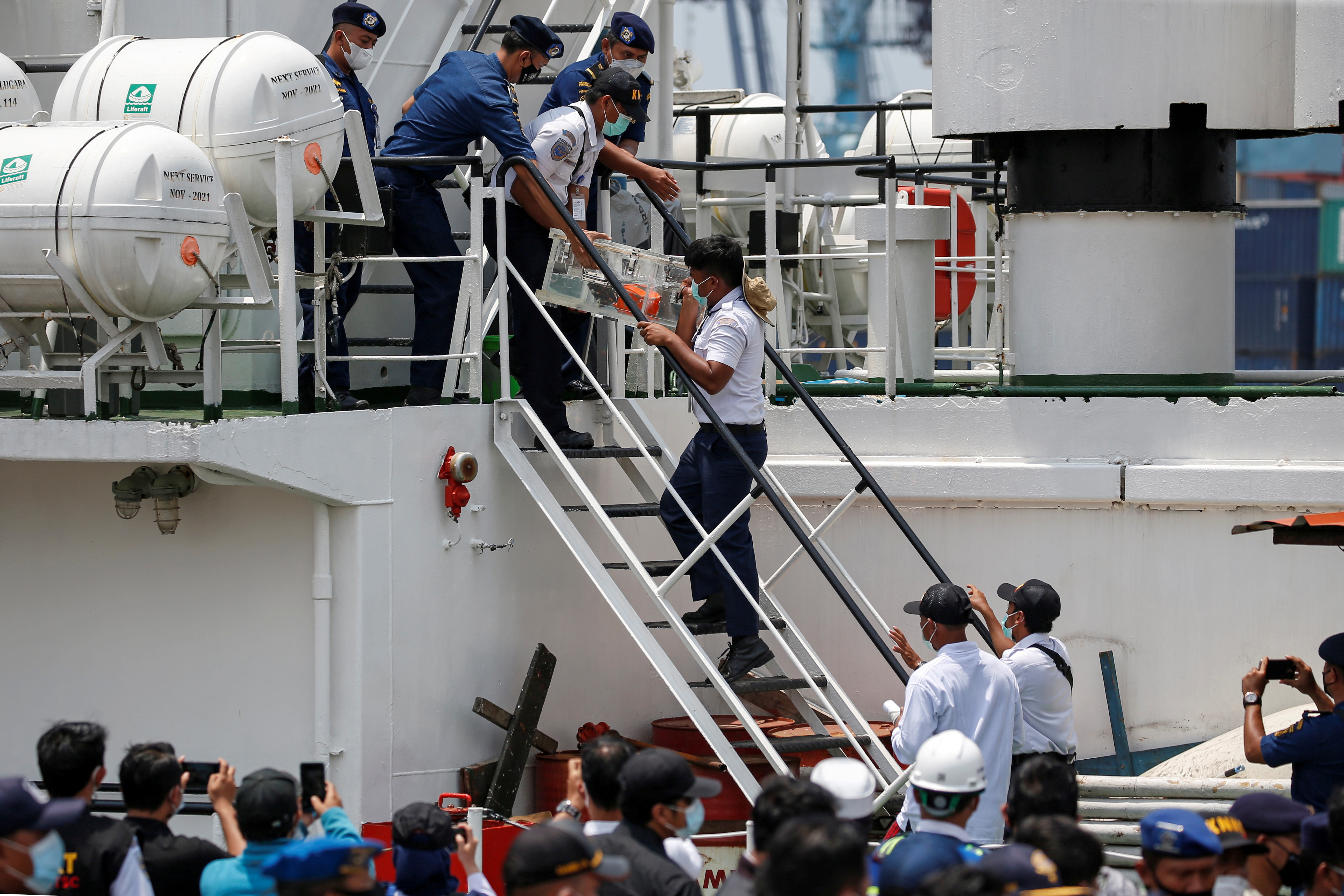 KNKT officials carry the Cockpit Voice Recorder (CVR) of Sriwijaya Air flight SJ 182 down a flight of stairs on an Indonesian Sea And Coast Guard vessel as it arrives at Tanjung Priok Port in Jakarta