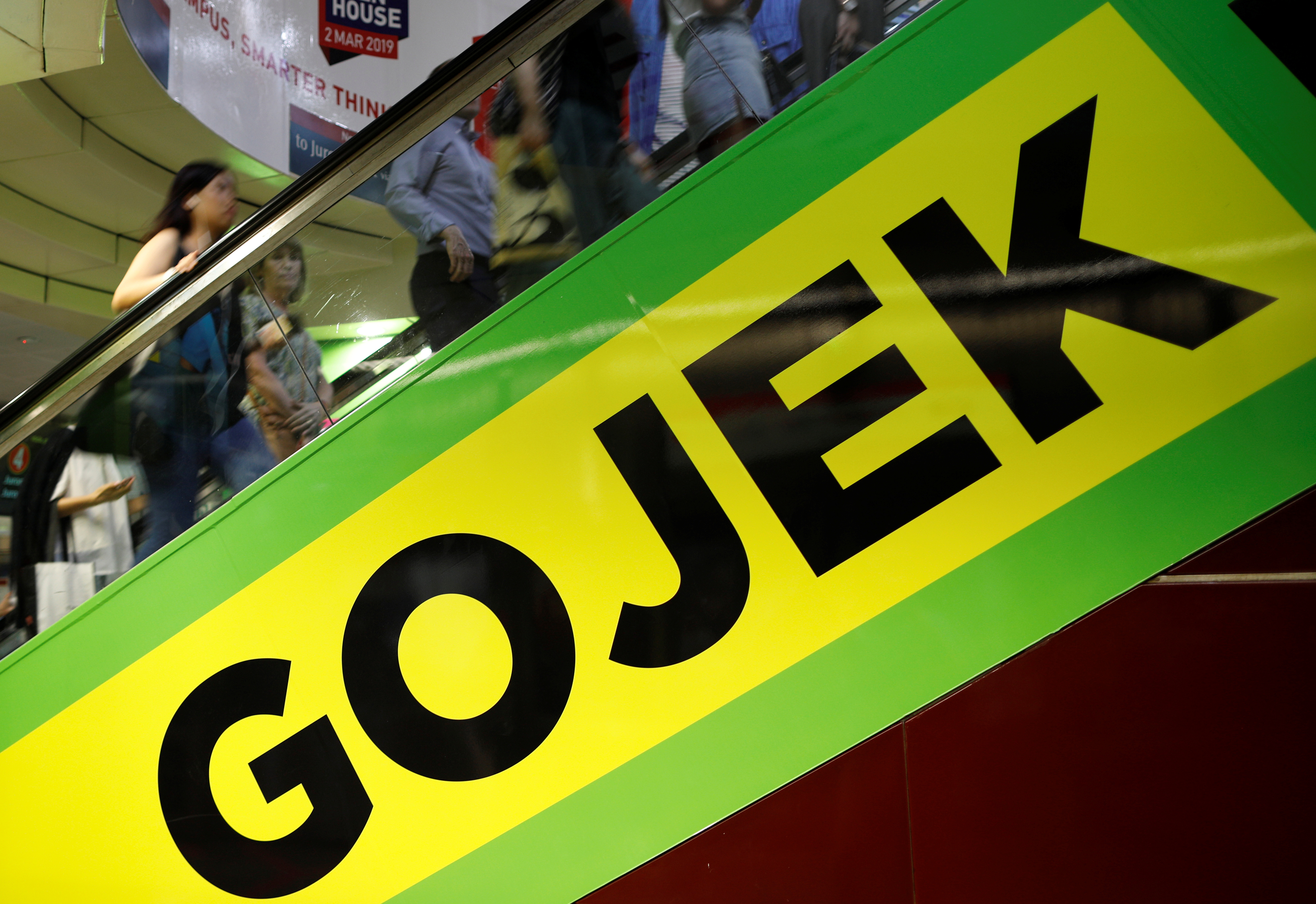 Commuters pass by a Gojek advertisement in Singapore