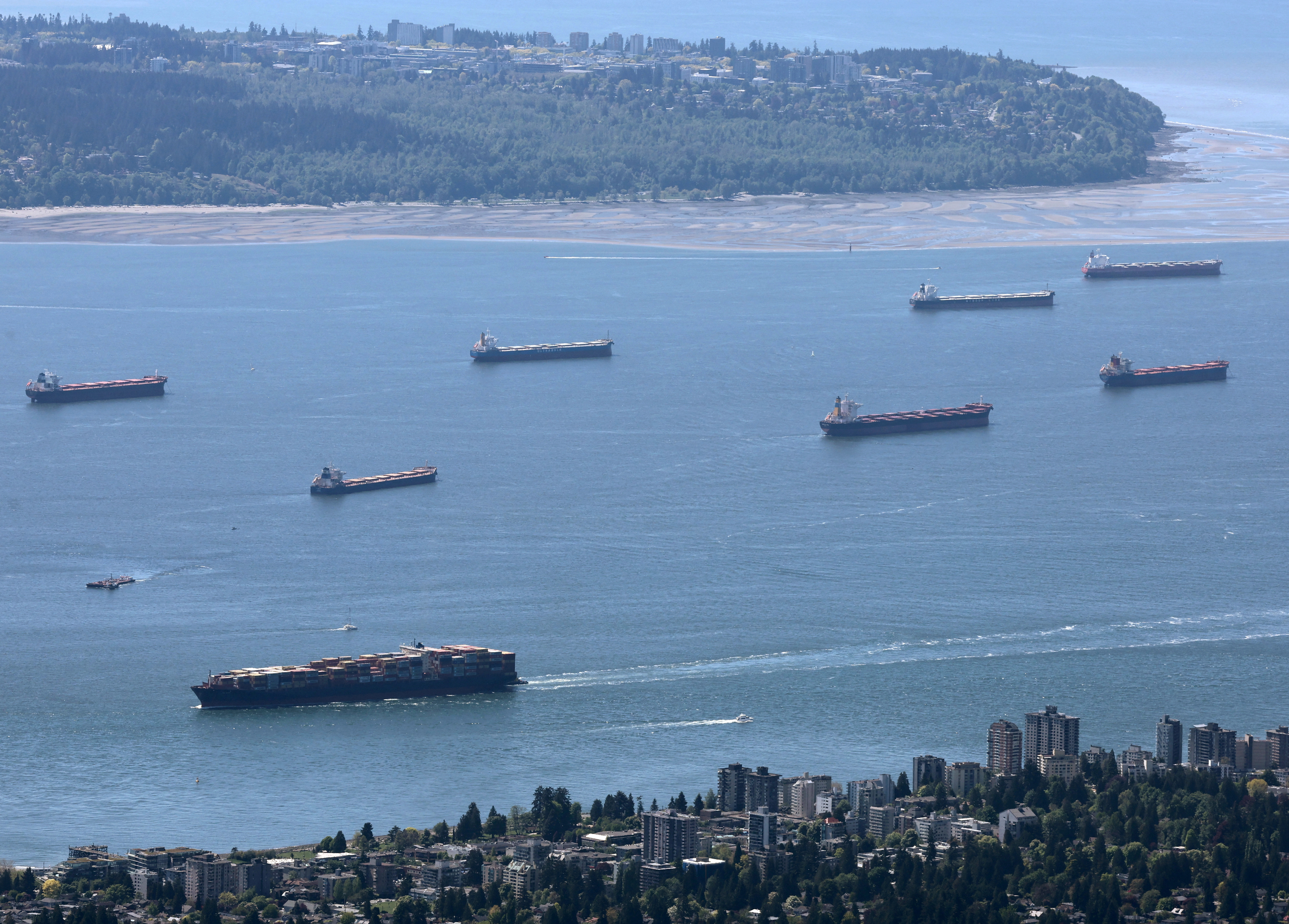 A container ship makes its way into the Port of Vancouver past vessels at anchor in English Bay