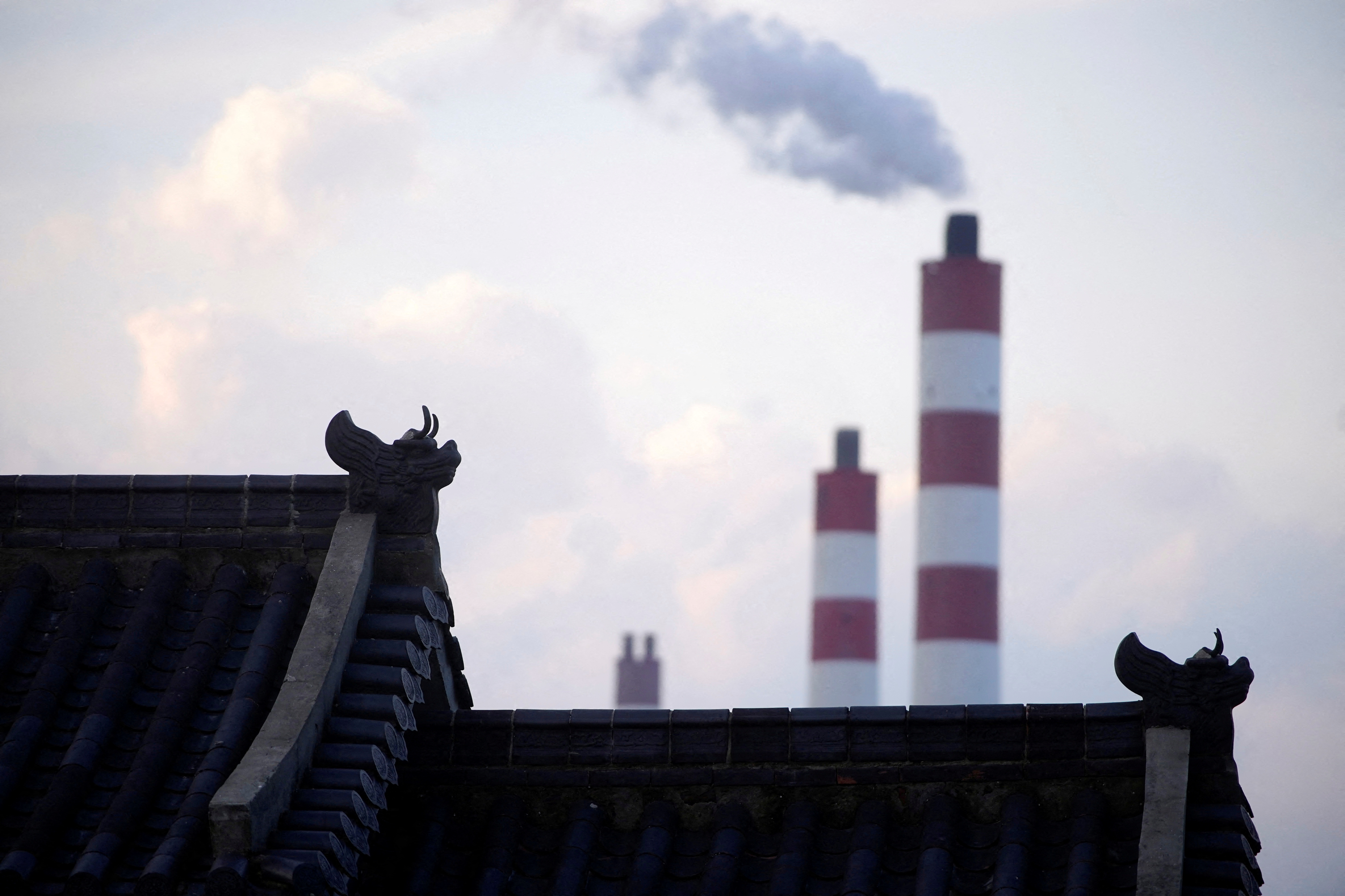 Chimneys of a coal-fired power plant are seen behind a gate in Shanghai
