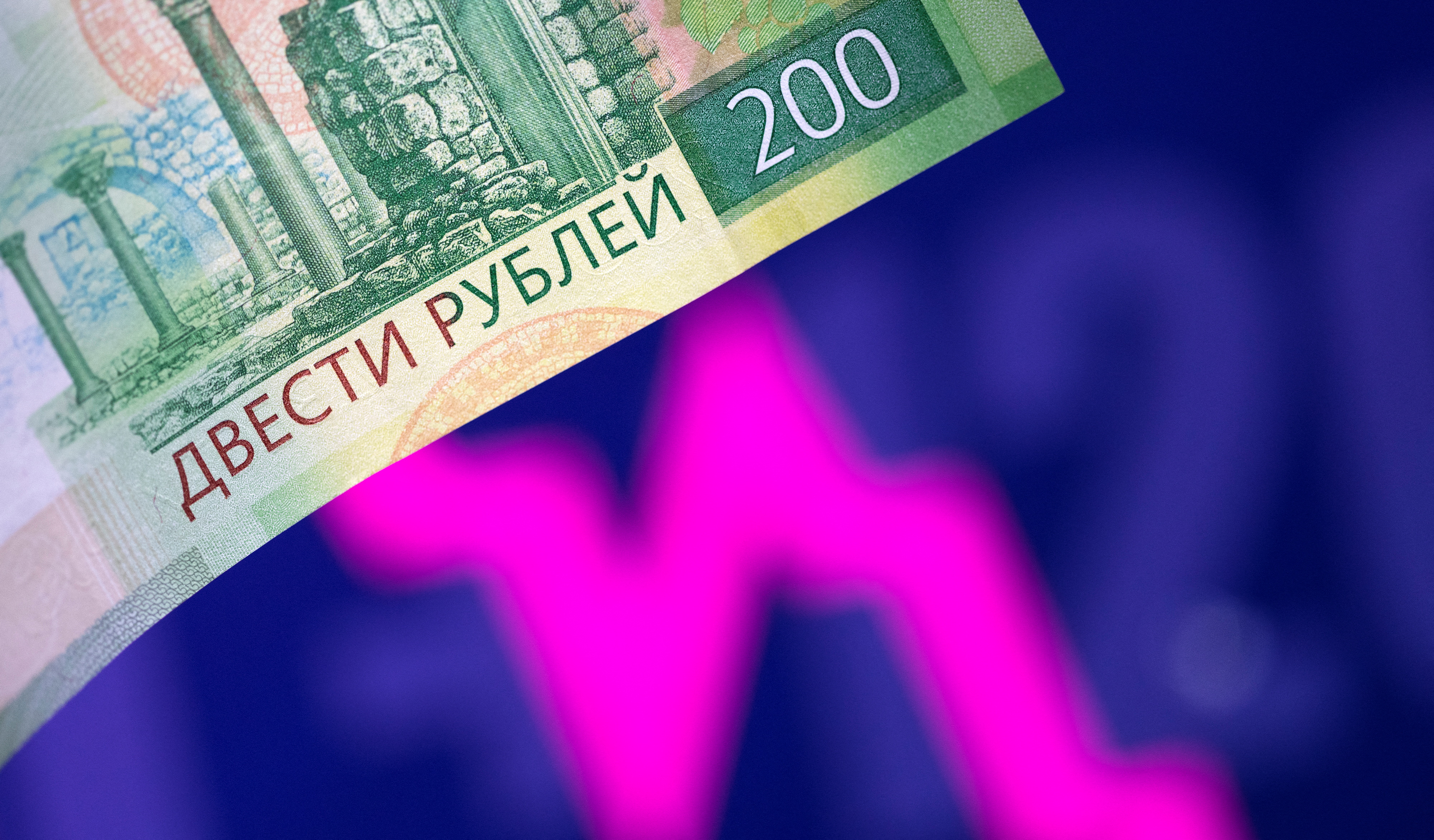 Illustration shows a Russian rouble banknote and a descending stock graph