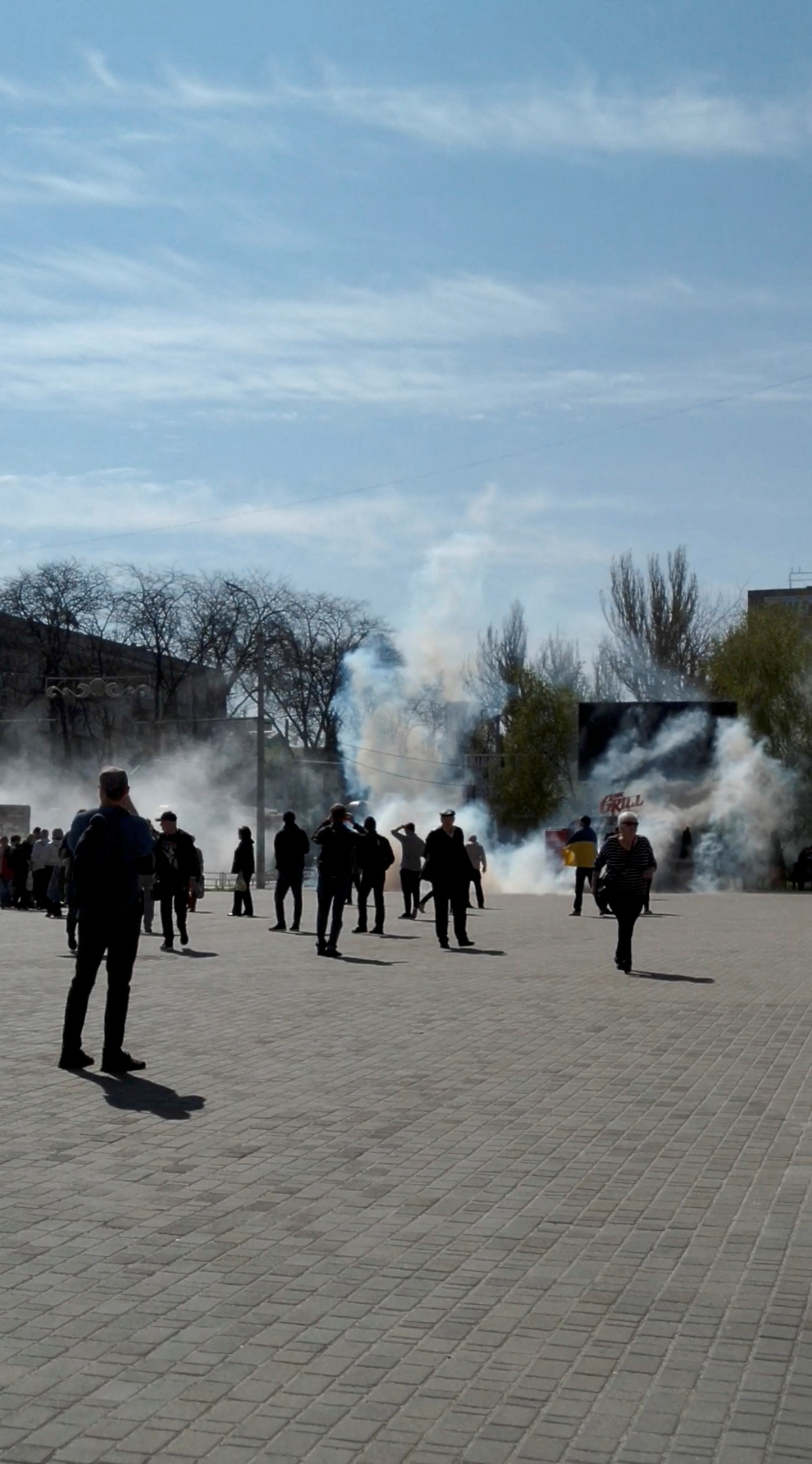 People flee as tear gas is fired during a protest, amid Russia's invasion of Ukraine, in Freedom Square