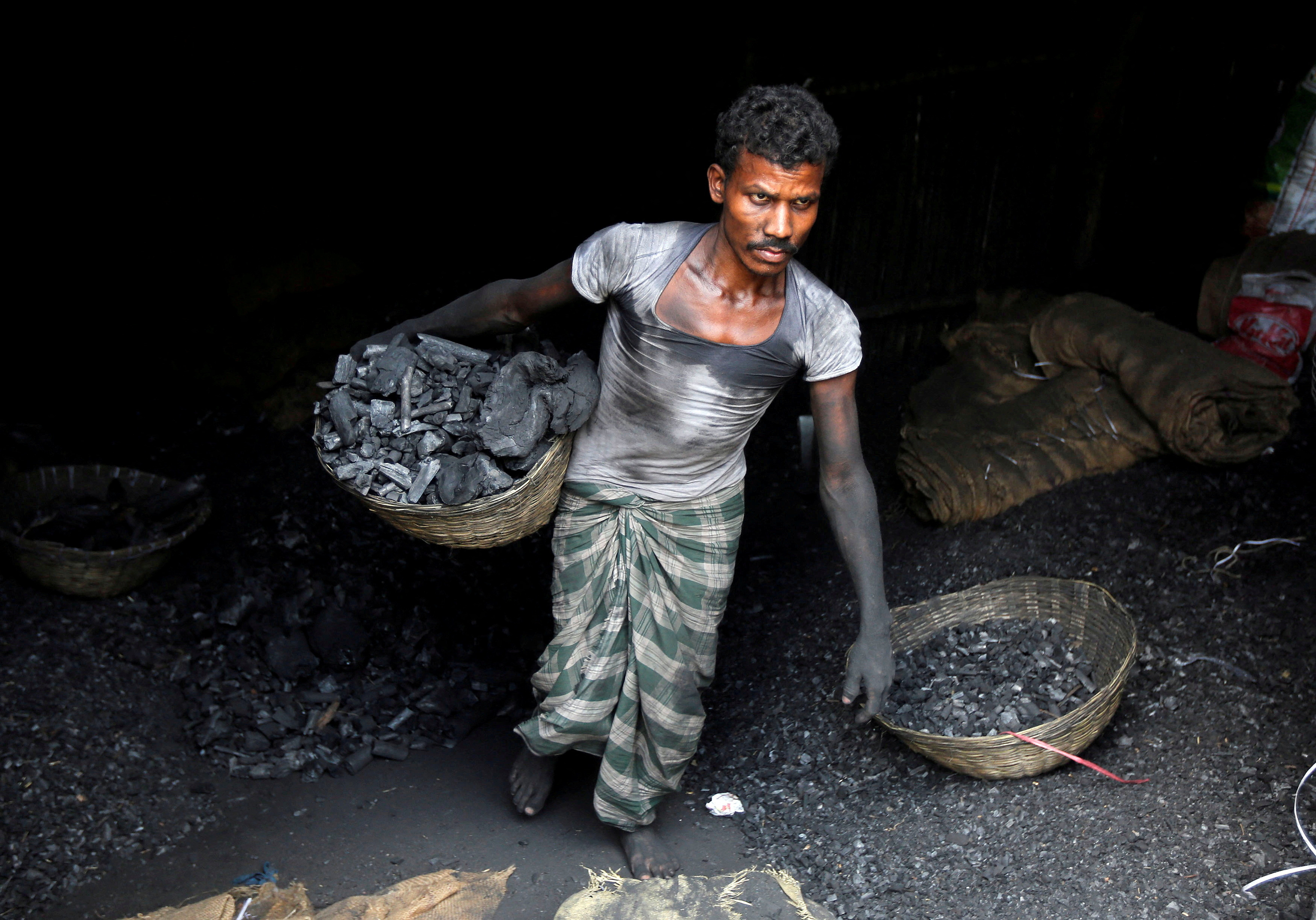 FILE PHOTO: A worker carries coal in a basket in a industrial area in Mumbai