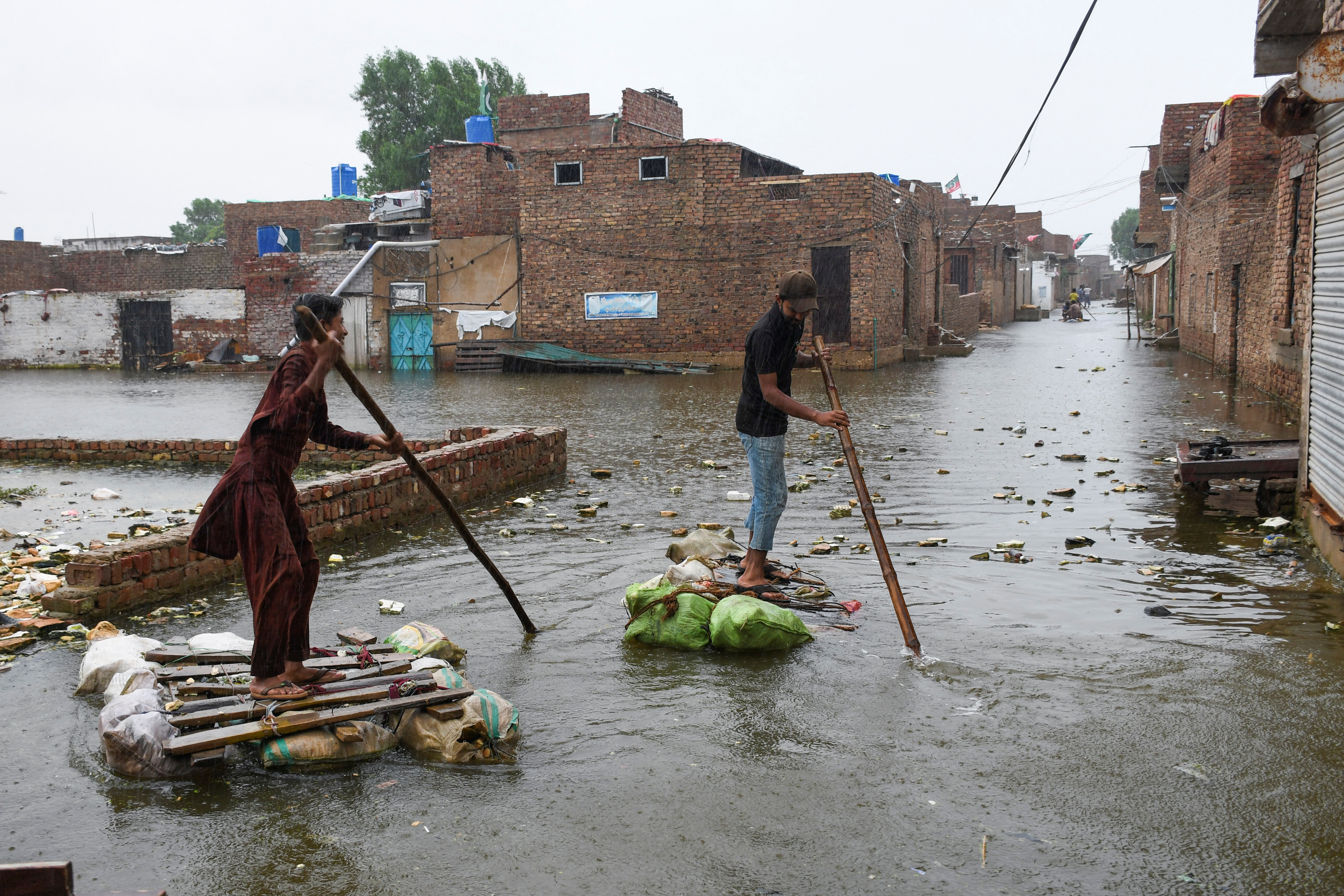 Men paddle on makeshift rafts as they cross a flooded street, amidst rainfall during the monsoon season in Hyderabad