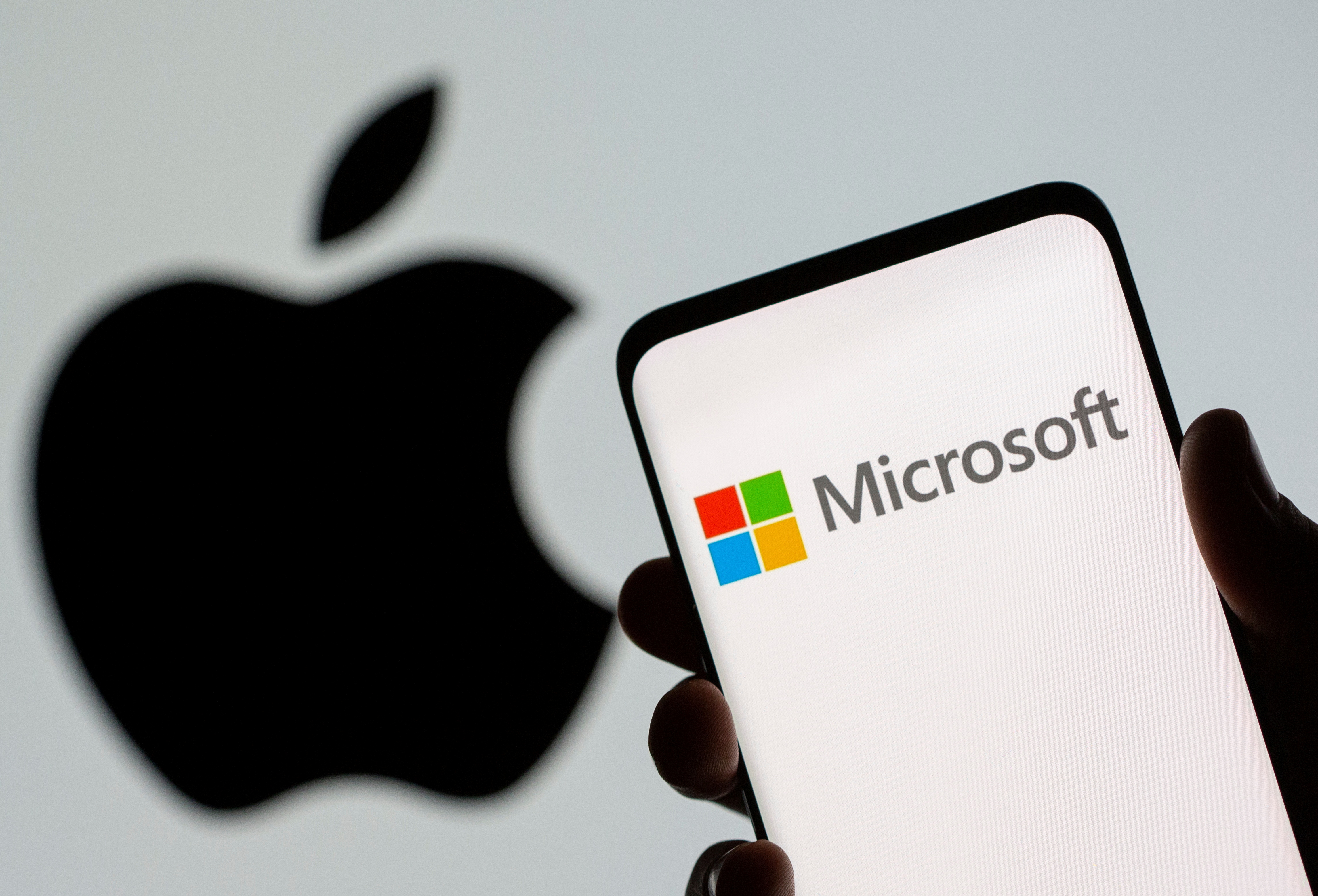 Microsoft logo is seen on the smartphone in front of displayed Apple logo in this illustration taken, July 26, 2021. REUTERS/Dado Ruvic/Illustration