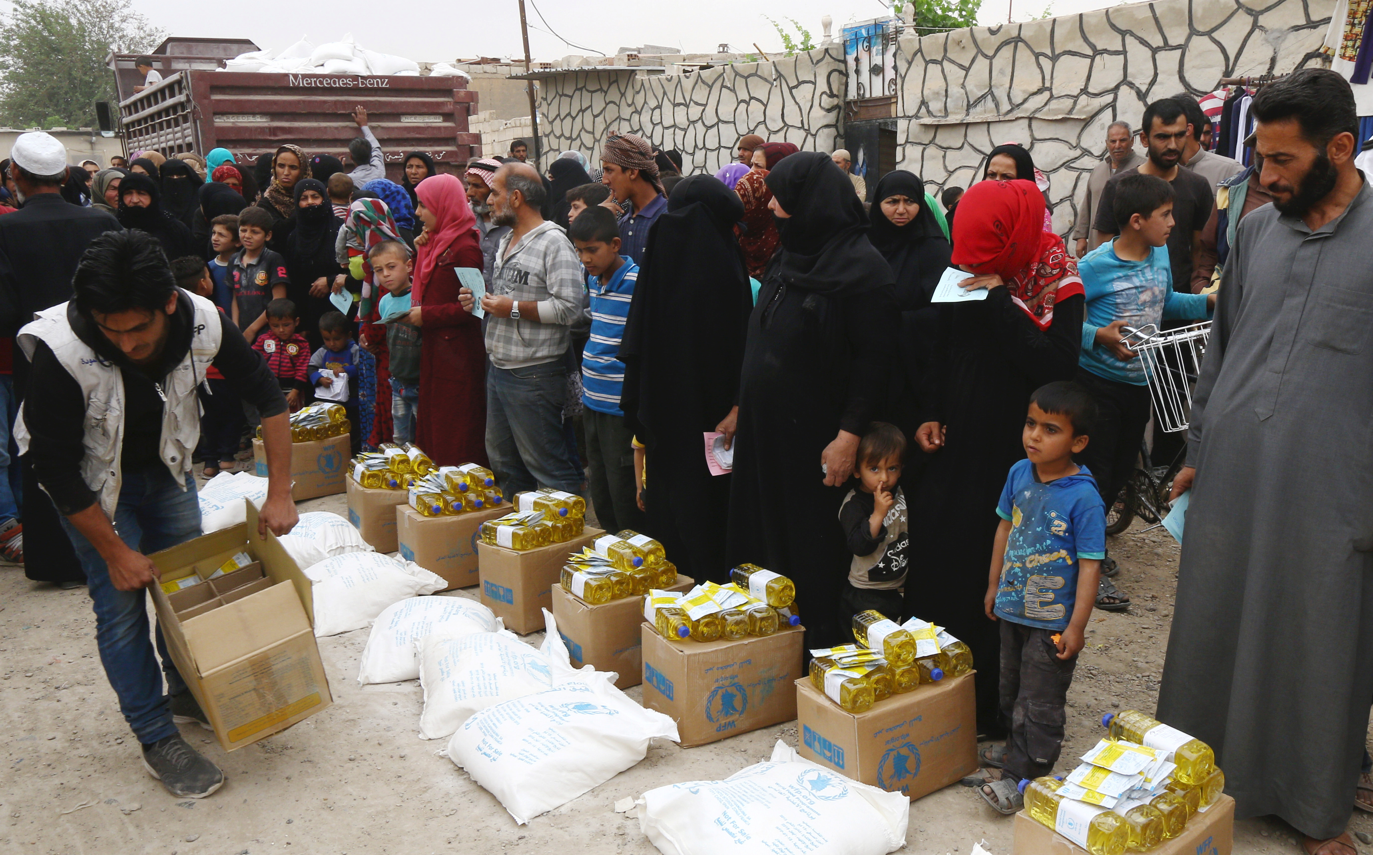People stand in a queue near the food aid given by UN's World Food Programme in Raqqa