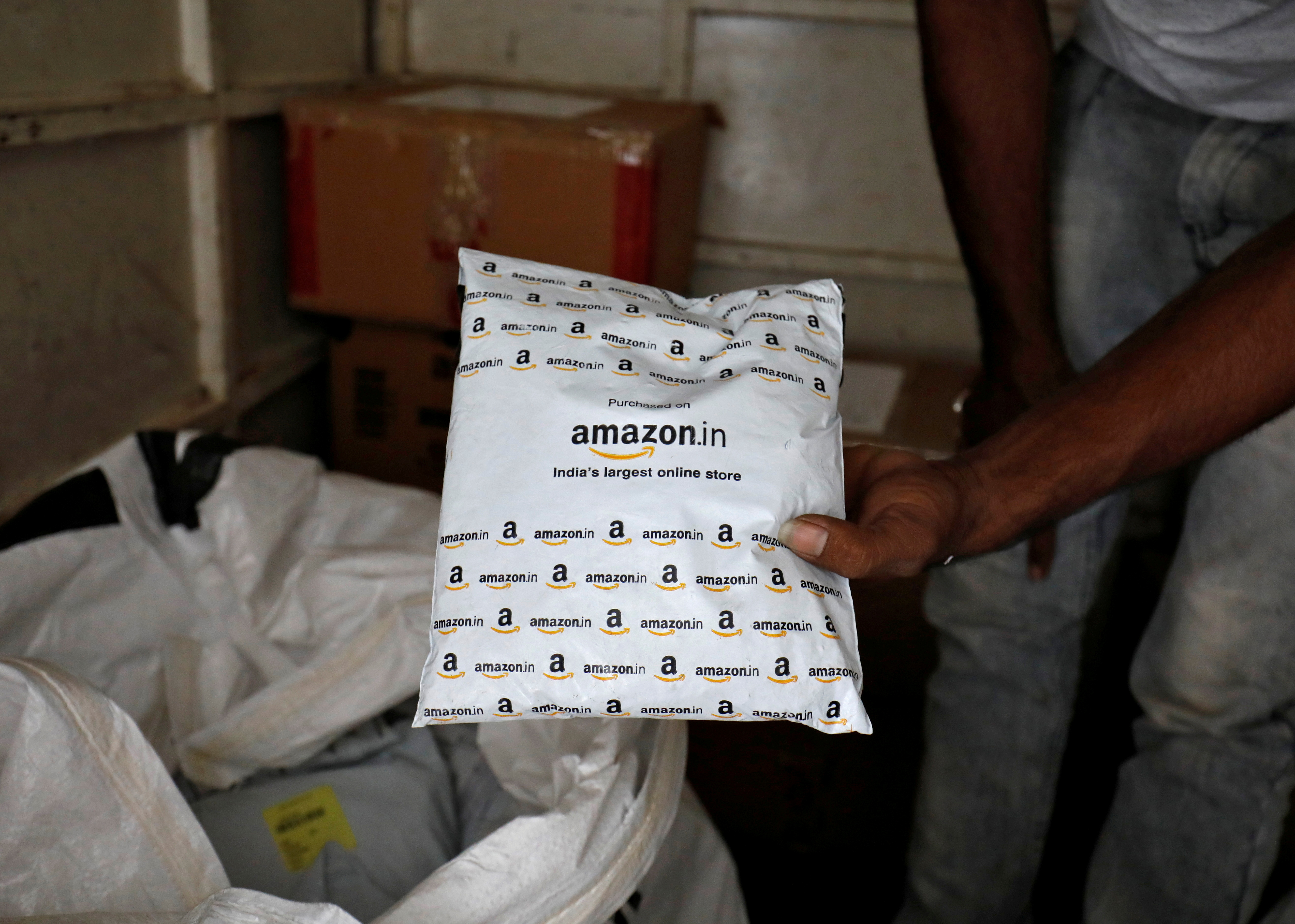 A worker sorts delivery packages in a van outside an Amazon facility in Ahmedabad