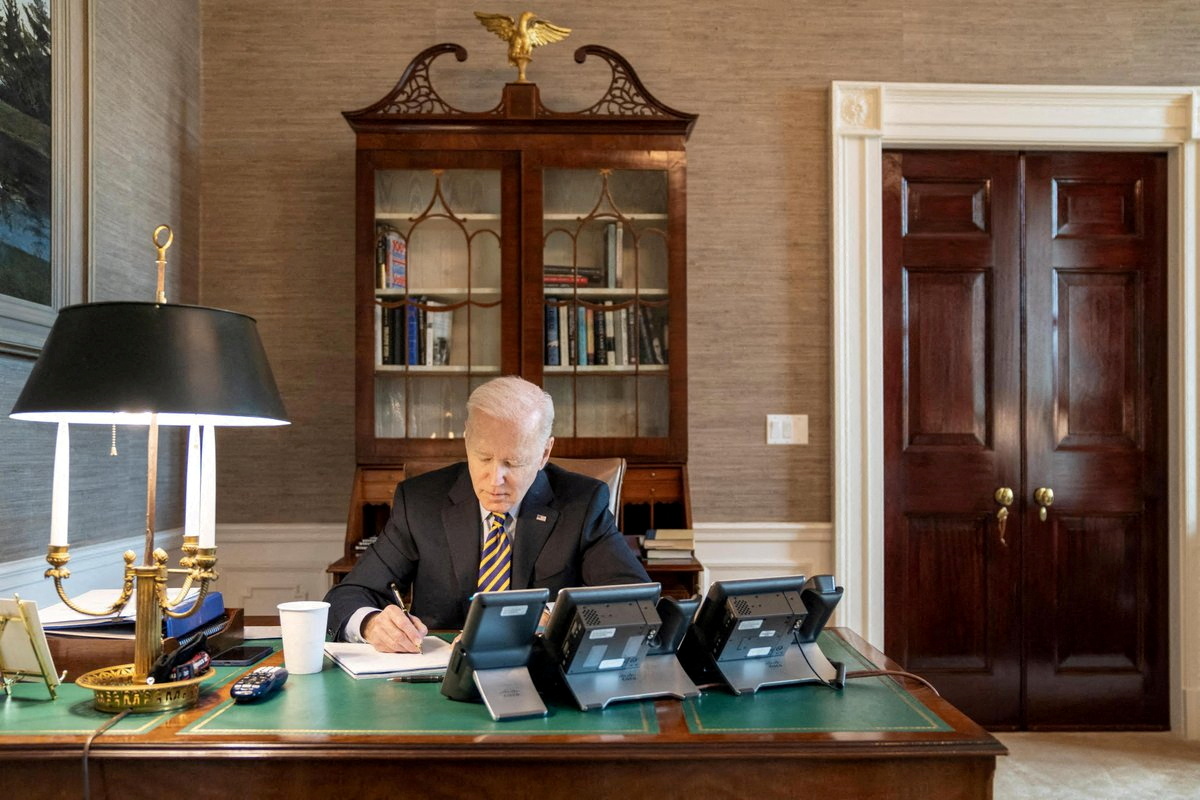 U.S. President Joe Biden writes at his desk in The White House in Washington