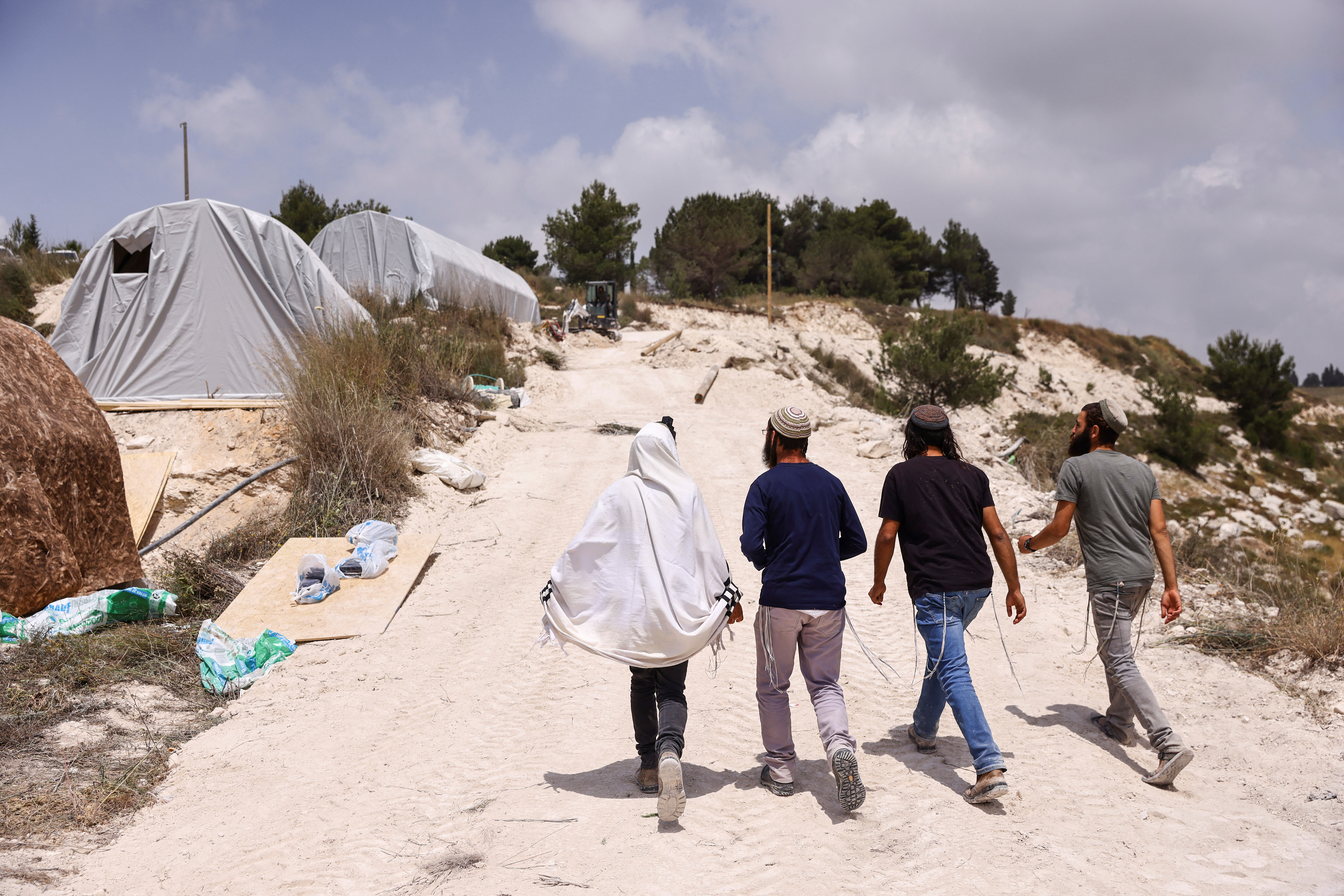 Israeli settlers walk past structures that were erected for a new Jewish seminary school, in the settler outpost of Homesh in the Israeli-occupied West Bank