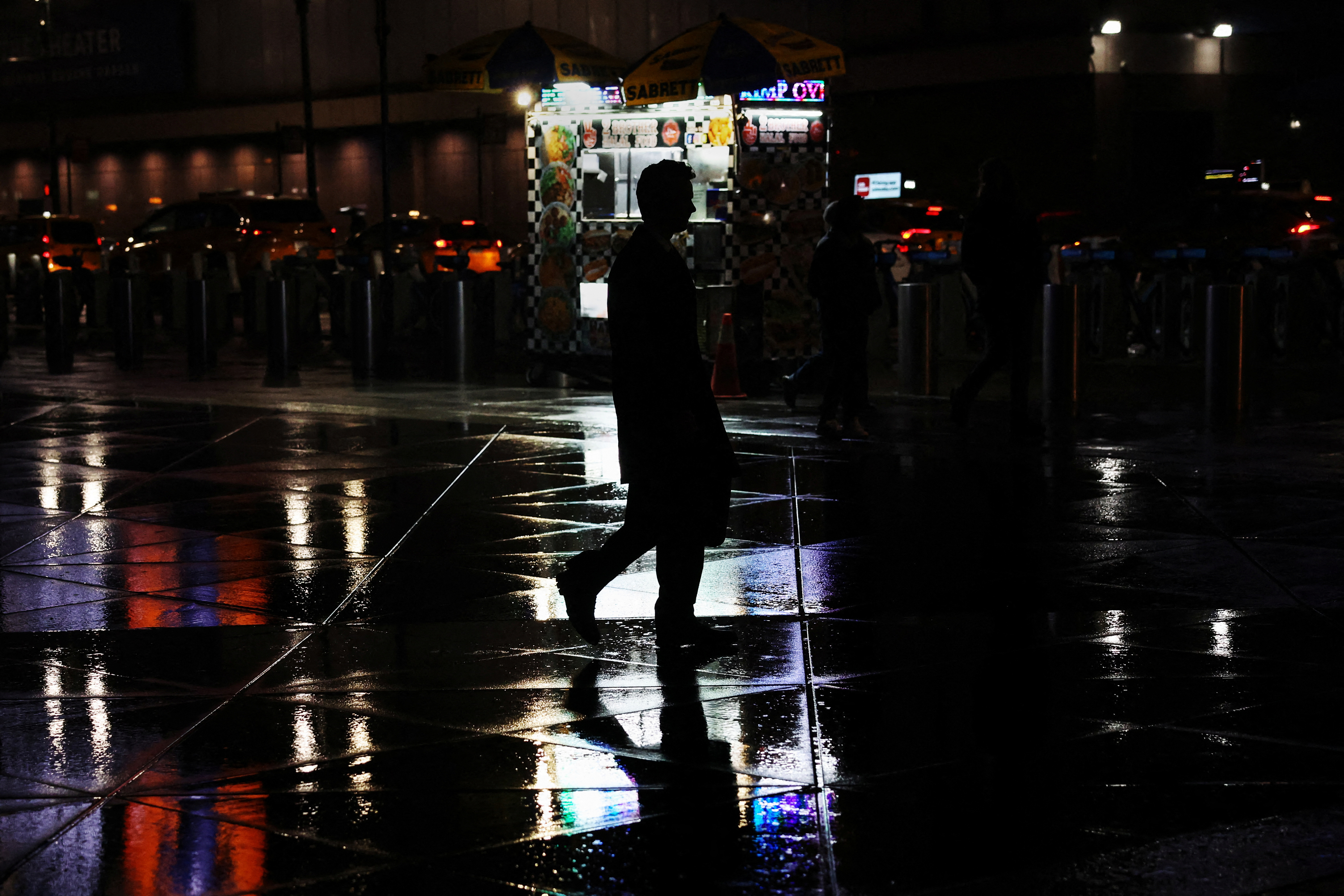 A man walks in silhouette during rainy weather across Pennsylvania Station in New York City