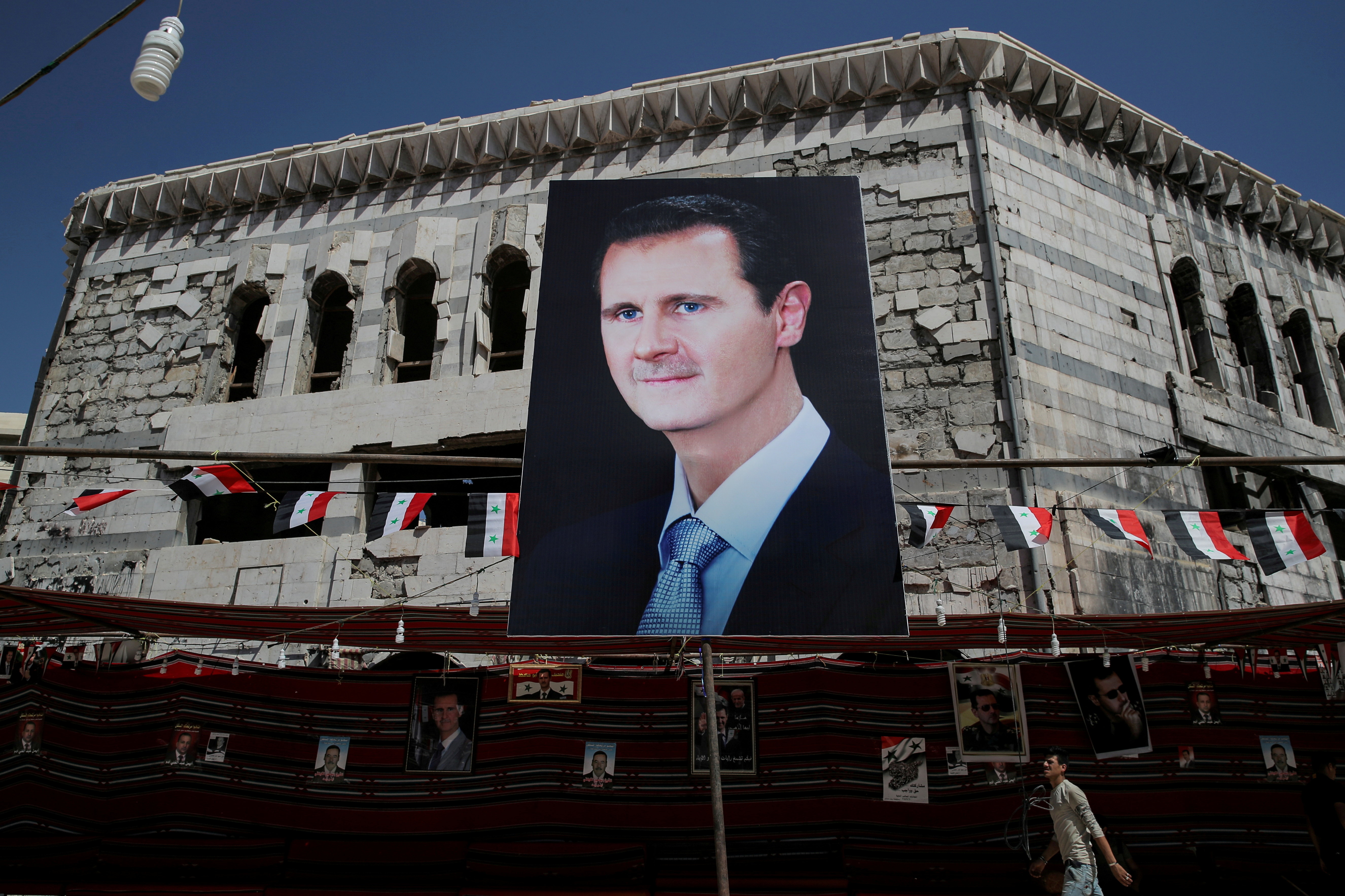 A man walks past a banner depicting Syrian president Bashar al-Assad in Douma