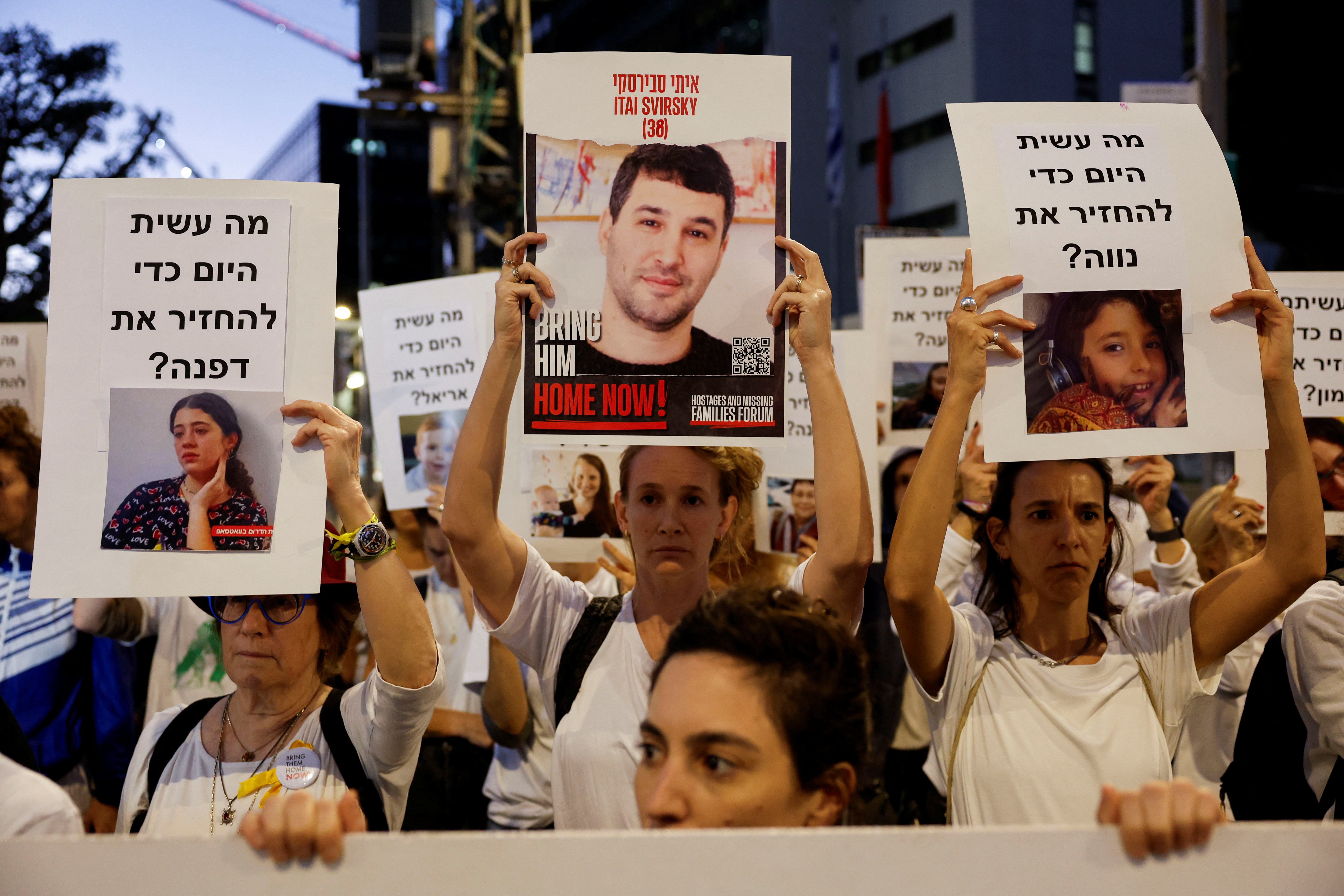 Israeli youth prepare an art installation of teddy bears with pictures of hostages, in Tel Aviv