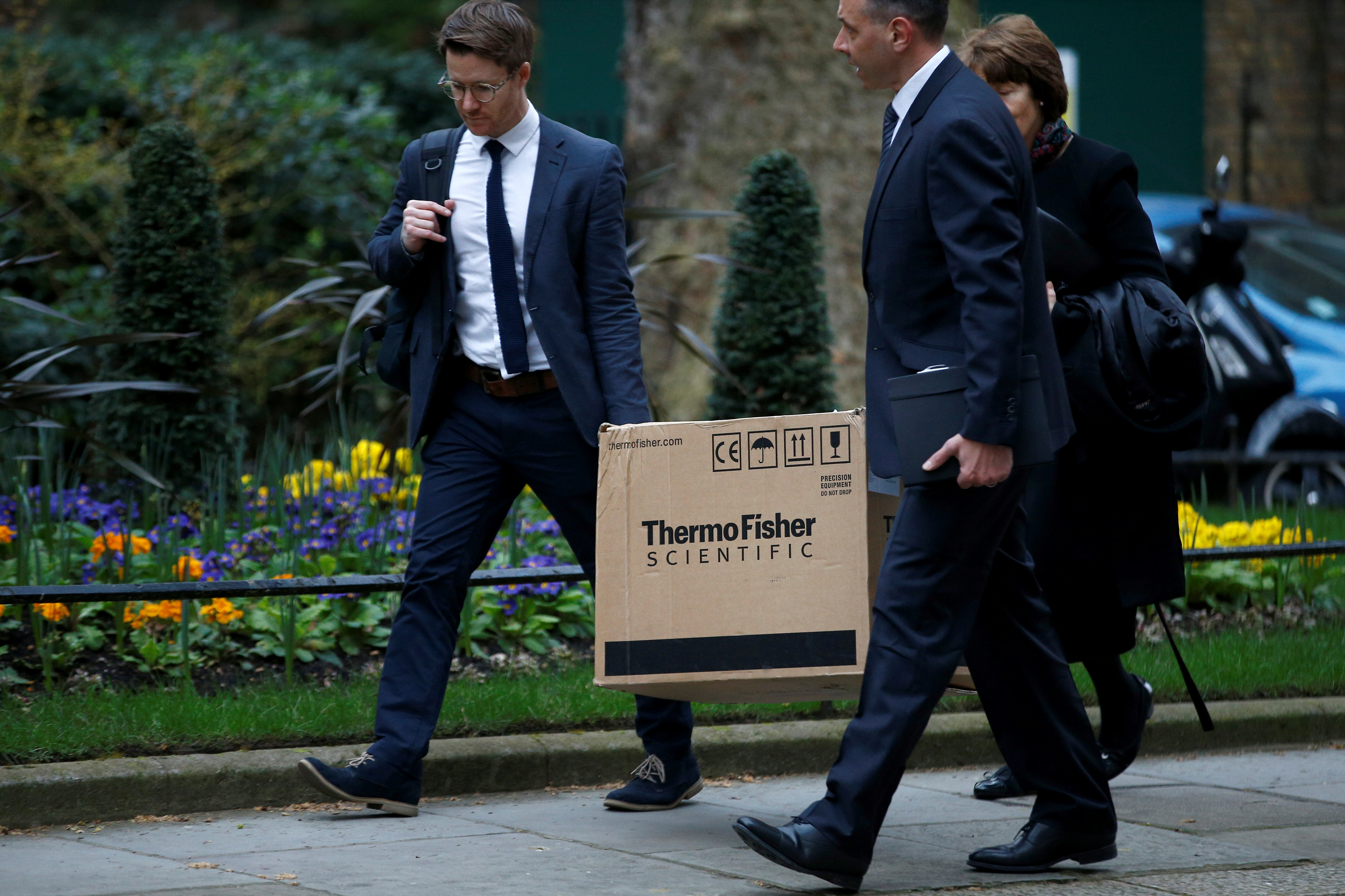 People carrying a box from ThermoFisher Scientific, a company that produces coronavirus tests, walk outside Downing Street, as the spread of the coronavirus disease (COVID-19) continues, in London