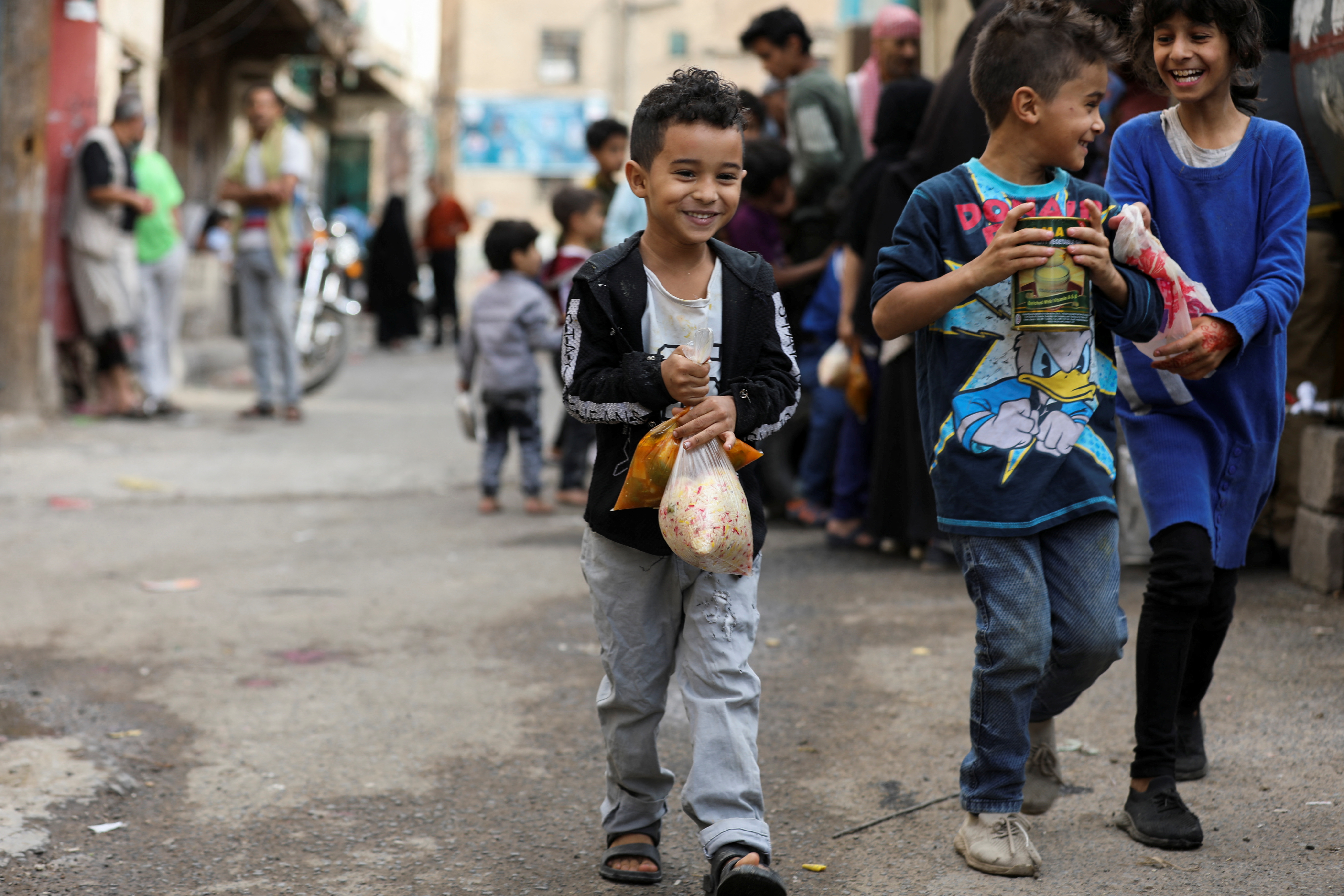 Boys walk after receiving meals from a charity kitchen during the holy month of Ramadan in Sanaa