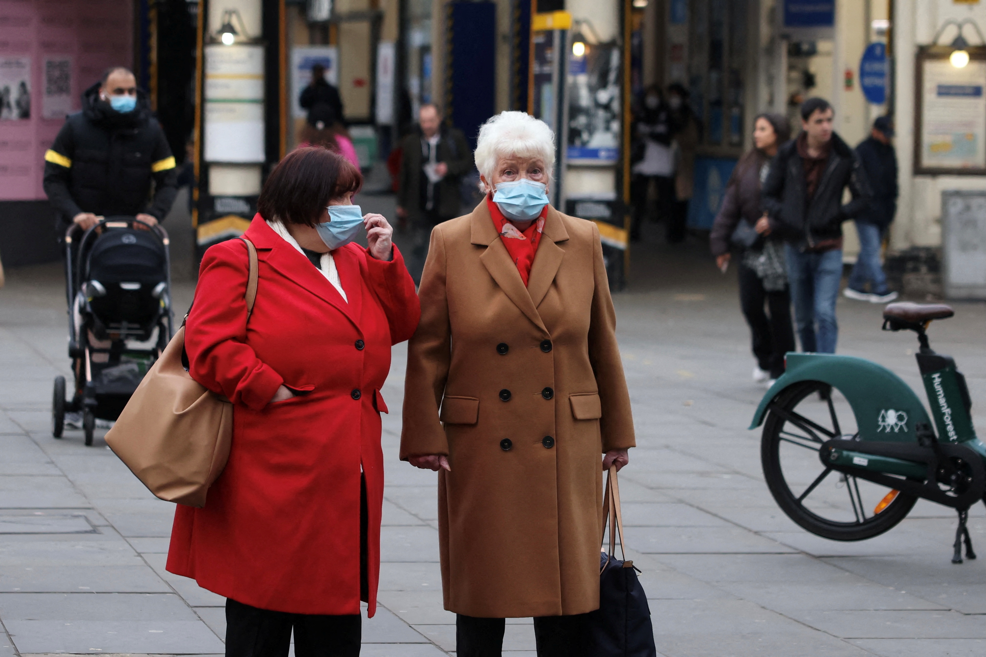 Women wearing face masks wait to cross a street in London