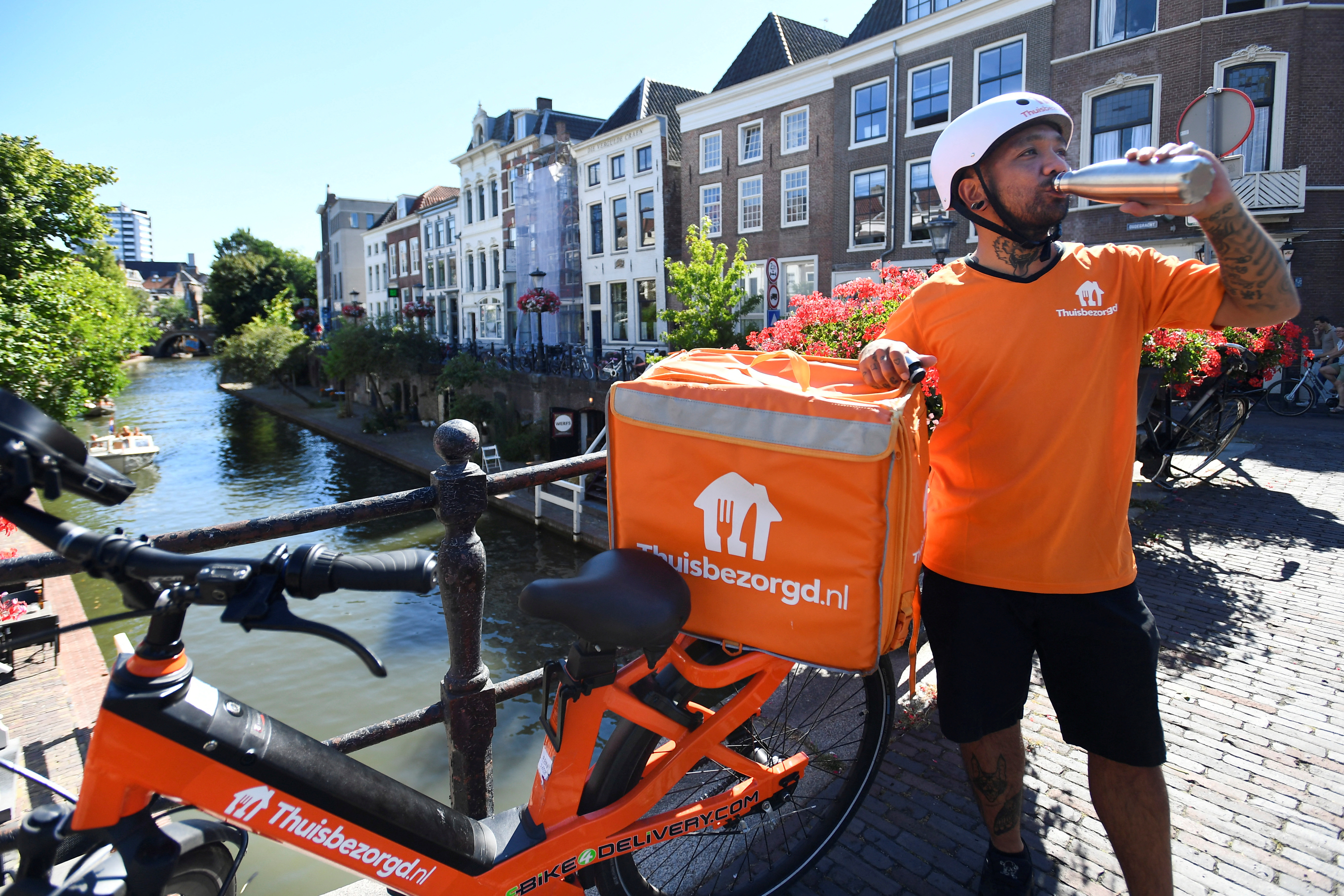 Bicycle courier Edward James Morta from Takeaway drinks water during the heatwave in Utrecht