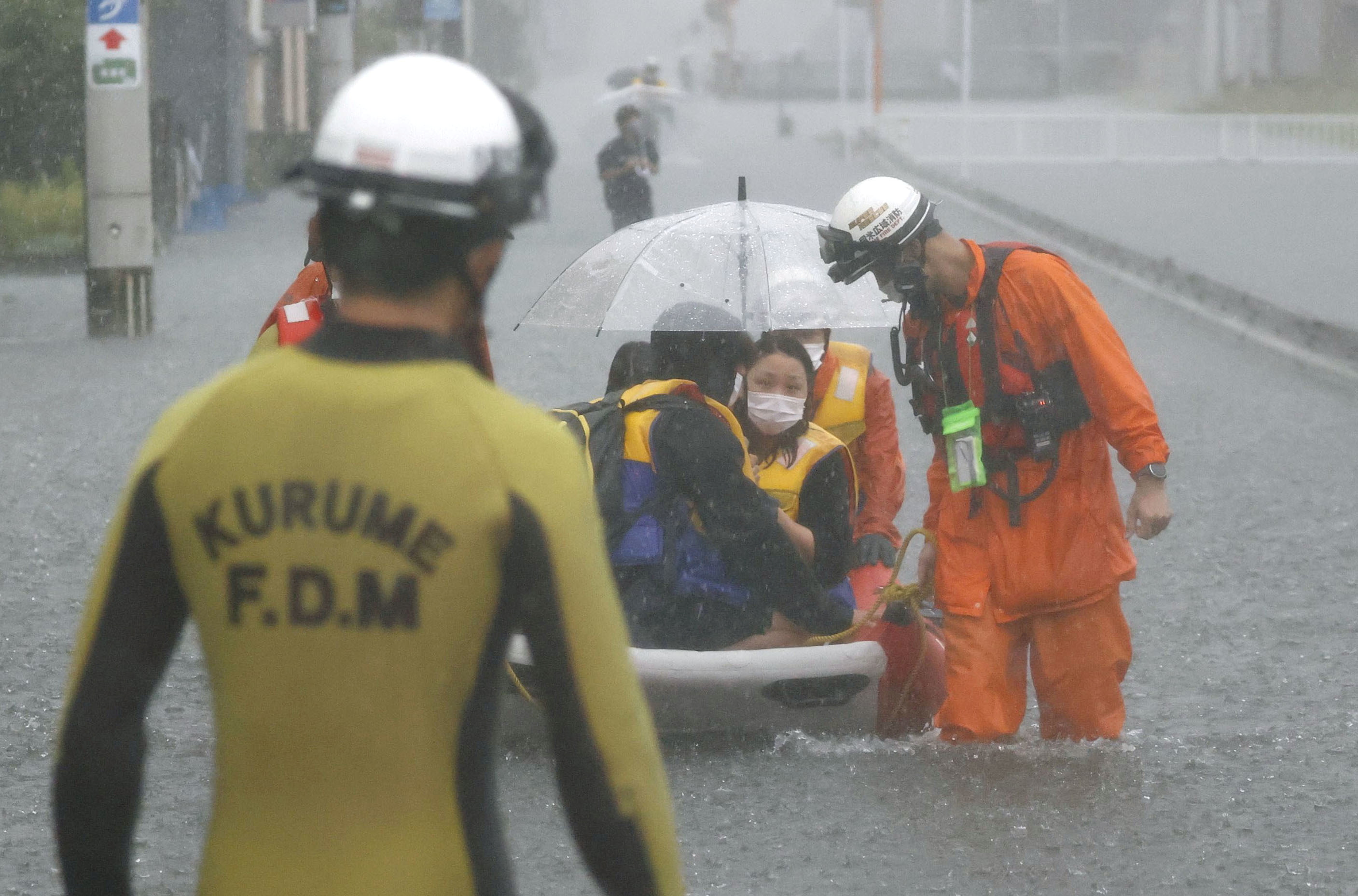 Firefighters transport stranded residents on a boat in a road flooded by heavy rain in Kurume, Fukuoka prefecture, western Japan, August 14, 2021, in this photo taken by Kyodo.  Mandatory credit Kyodo/via REUTERS  