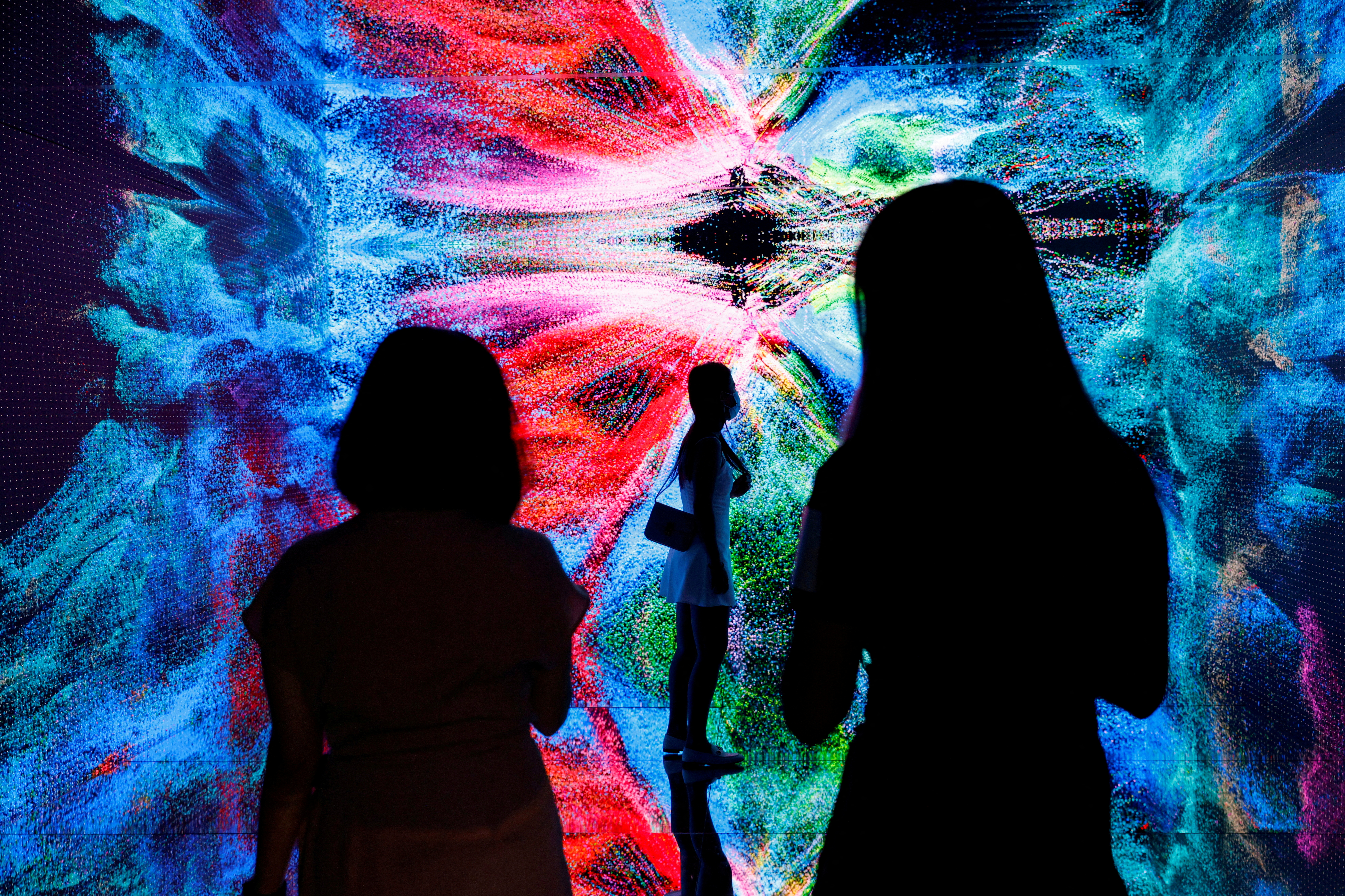 Visitors are pictured in front of an immersive art installation titled "Machine Hallucinations - Space: Metaverse" by media artist Refik Anadol at the Digital Art Fair, in Hong Kong