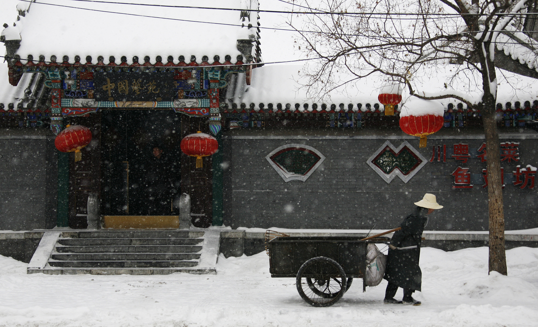 A cleaner pulls his cart along a snow-covered footpath in central Beijing