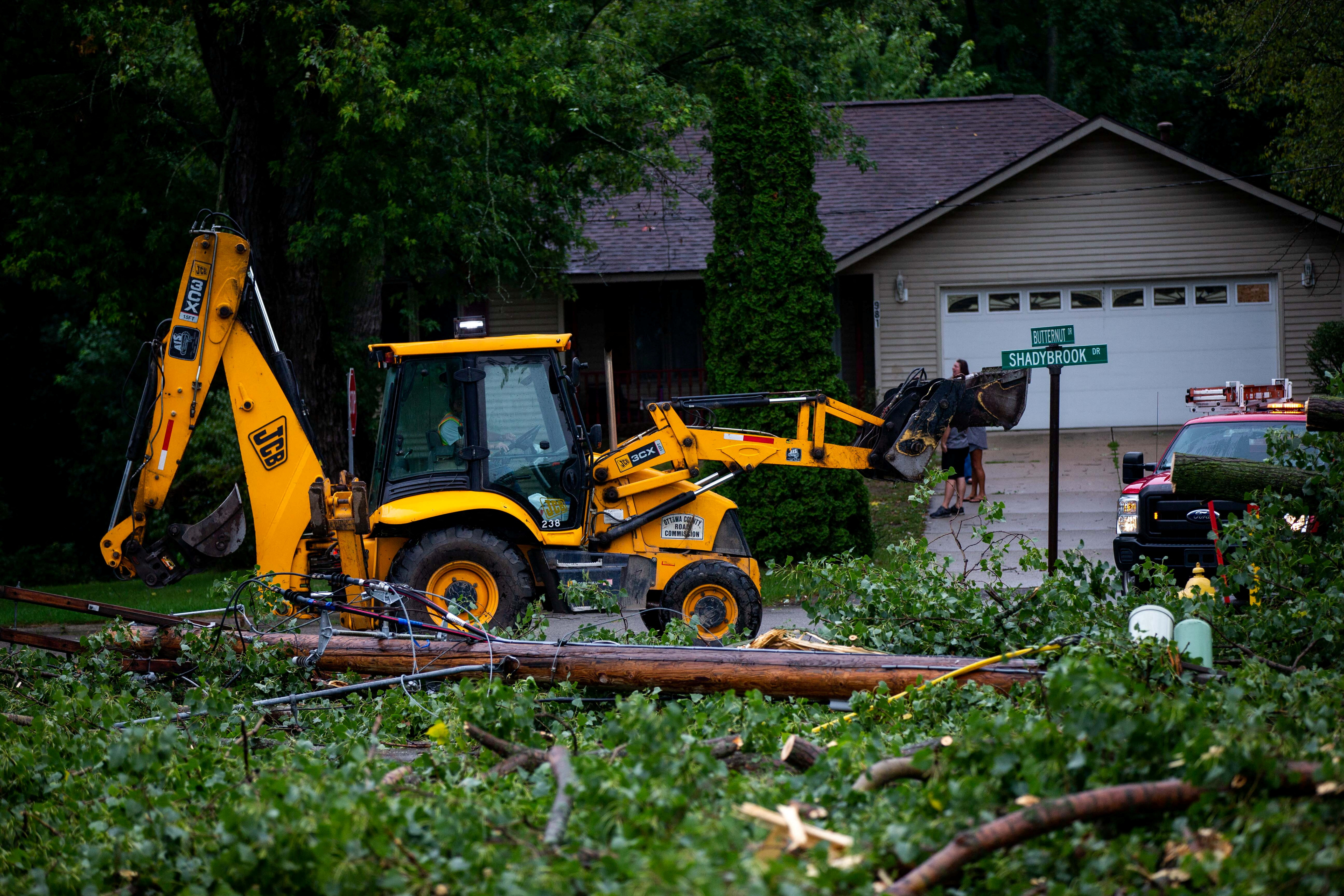 Fallen tree limbs are cleared after thunderstorms and high winds downed power lines and closed roads in Holland