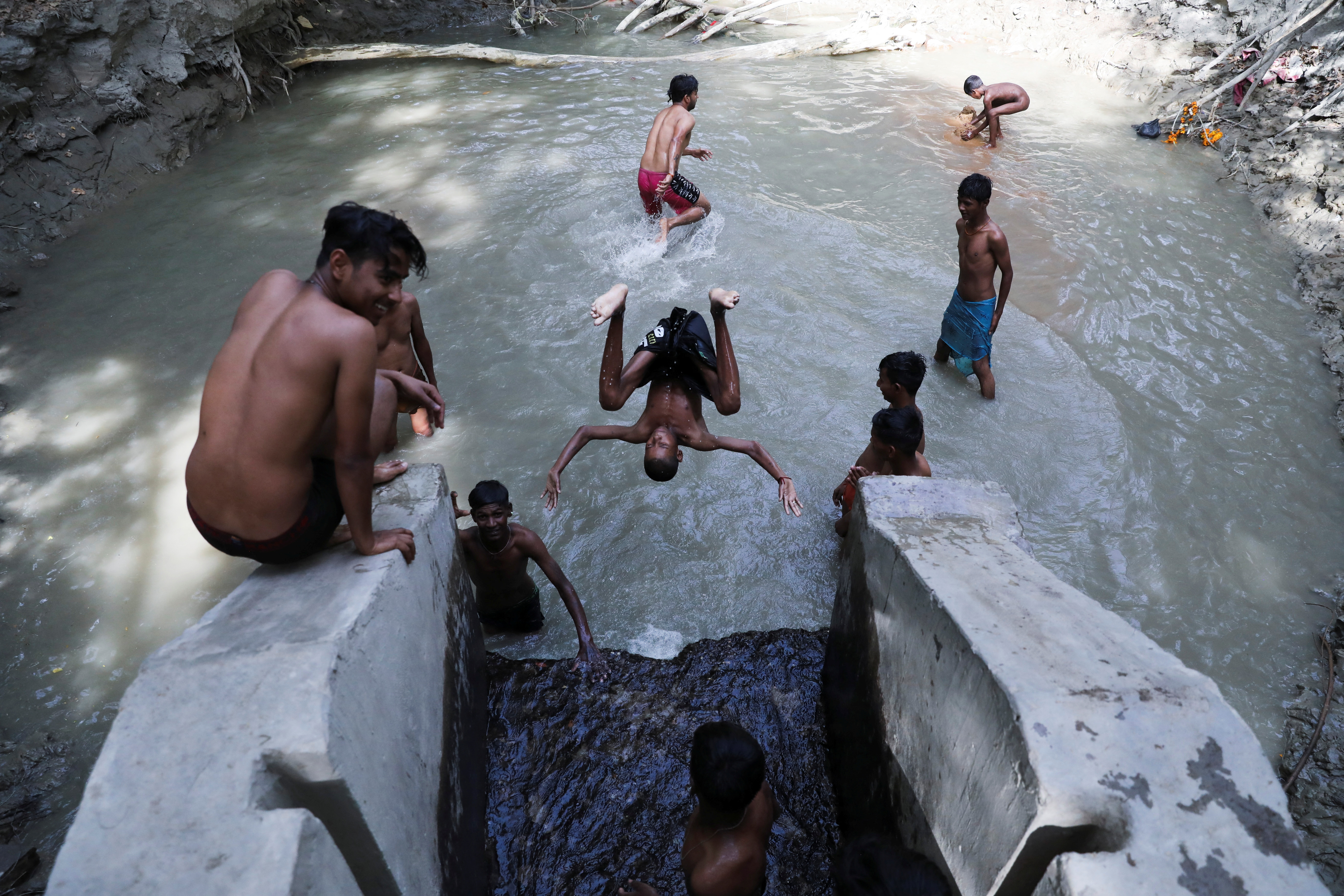 Boys cool themselves in a pool of water near a highway on a hot summer day, in New Delhi