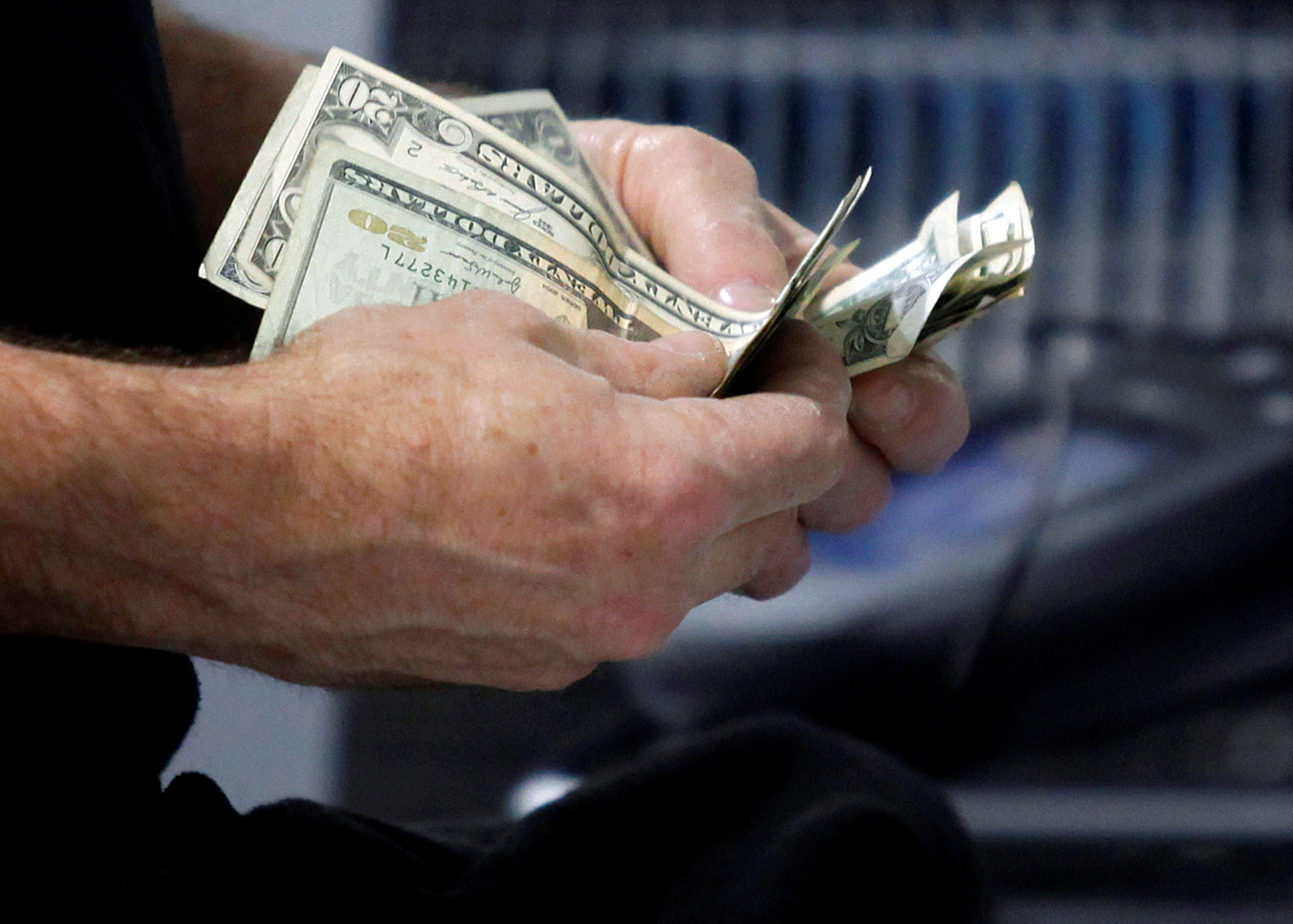 FILE PHOTO: A customer counts his cash at the register while purchasing an item at a Best Buy store in Flushing