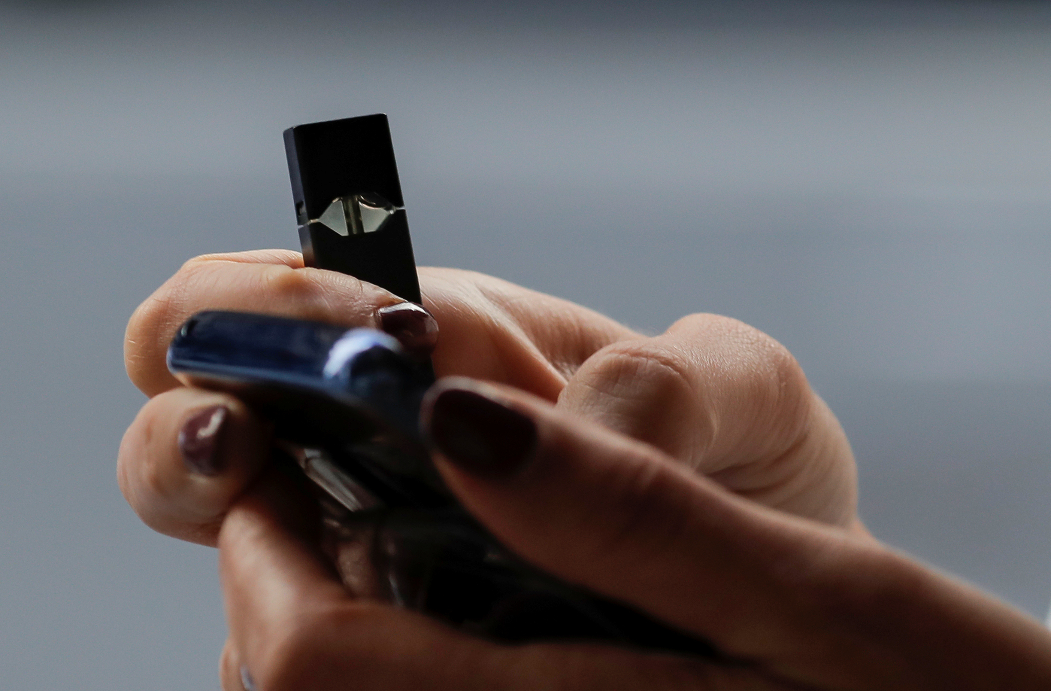 A woman holds a Juul e-cigarette while walking in New York