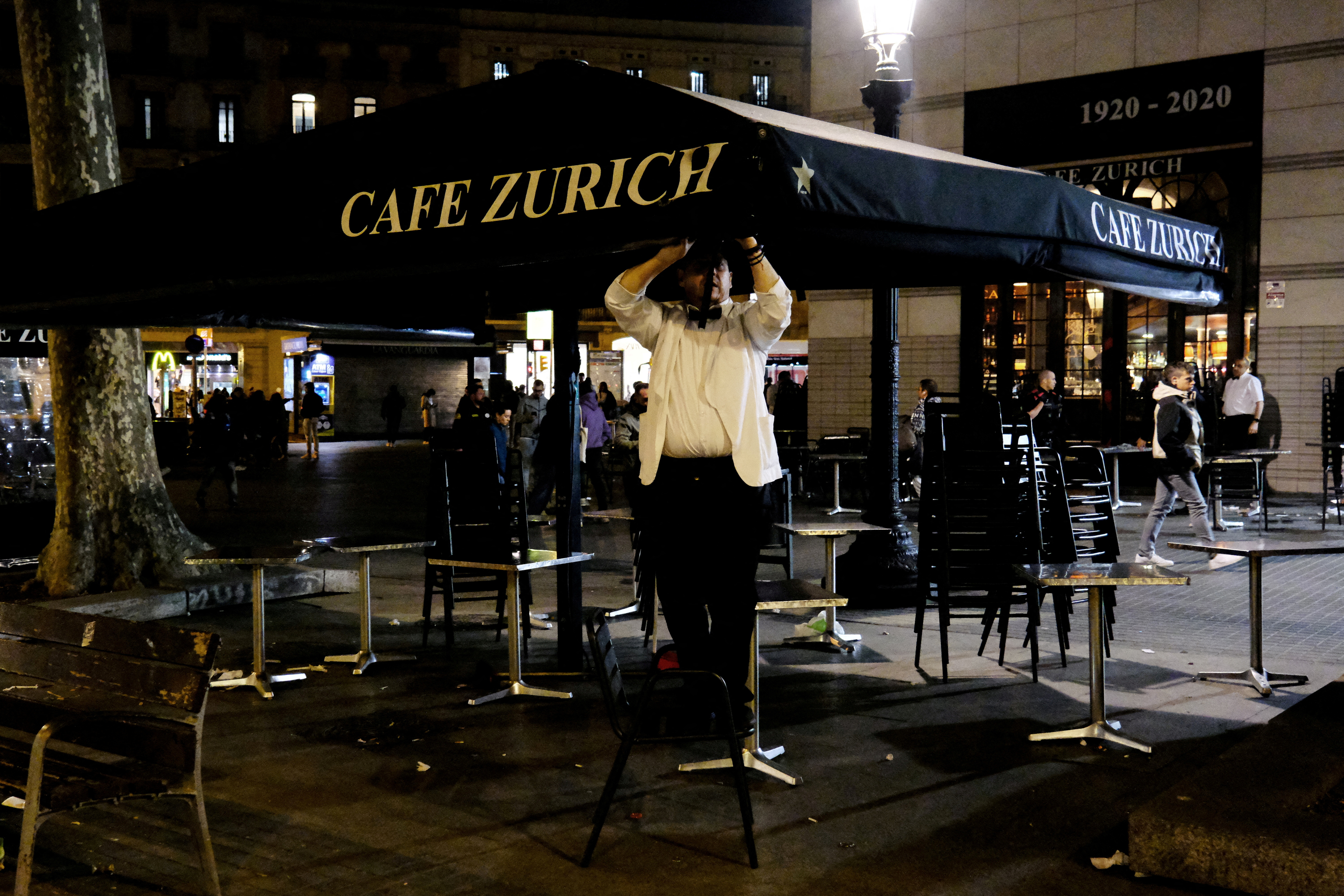 A waiter picks up the terrace of the Zurich bar at Placa de Catalunya in Barcelona, Spain