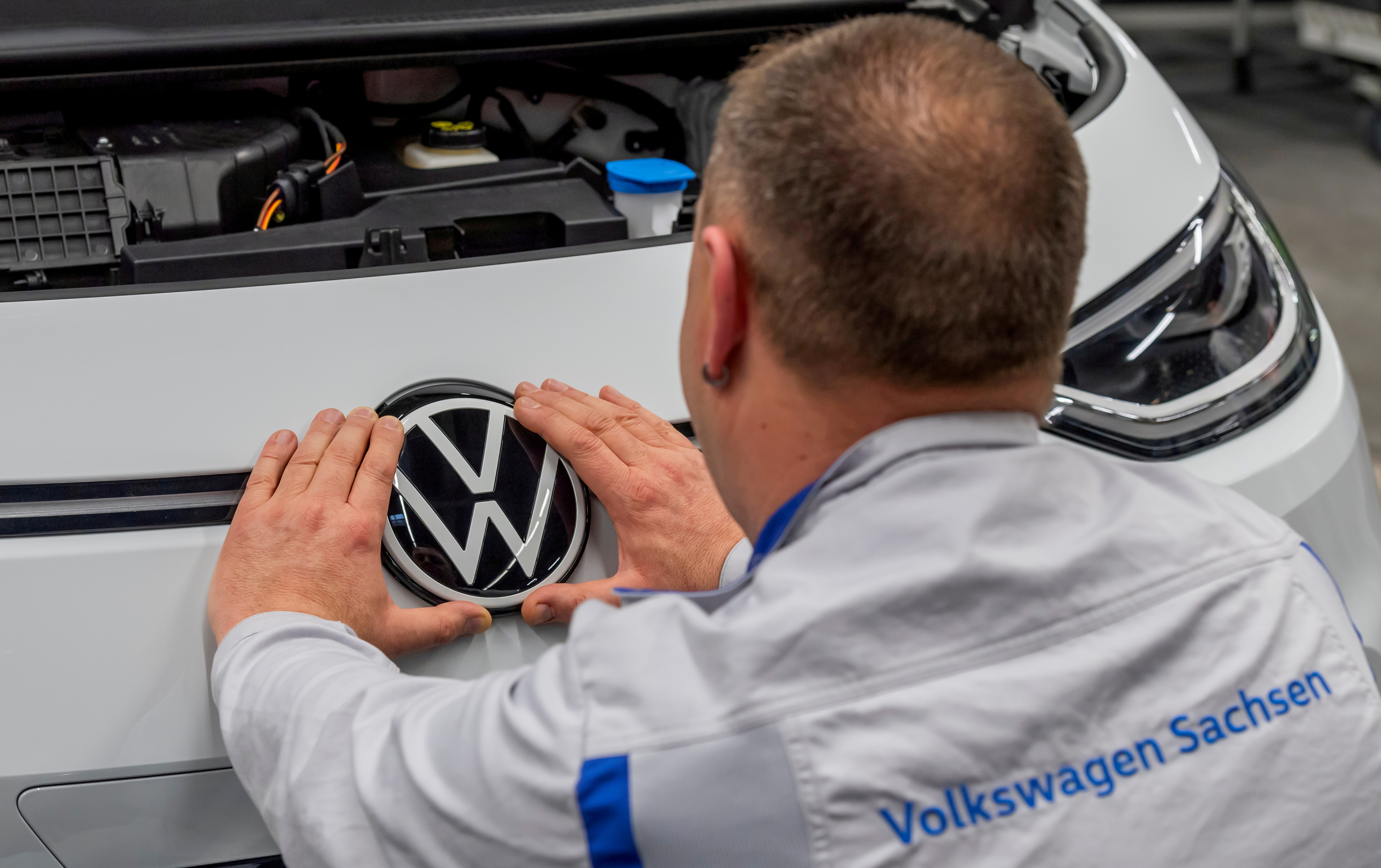 An employee fixes a VW sign at a production line of the electric Volkswagen model ID.3 in Zwickau, Germany, February 25, 2020. REUTERS/Matthias Rietschel