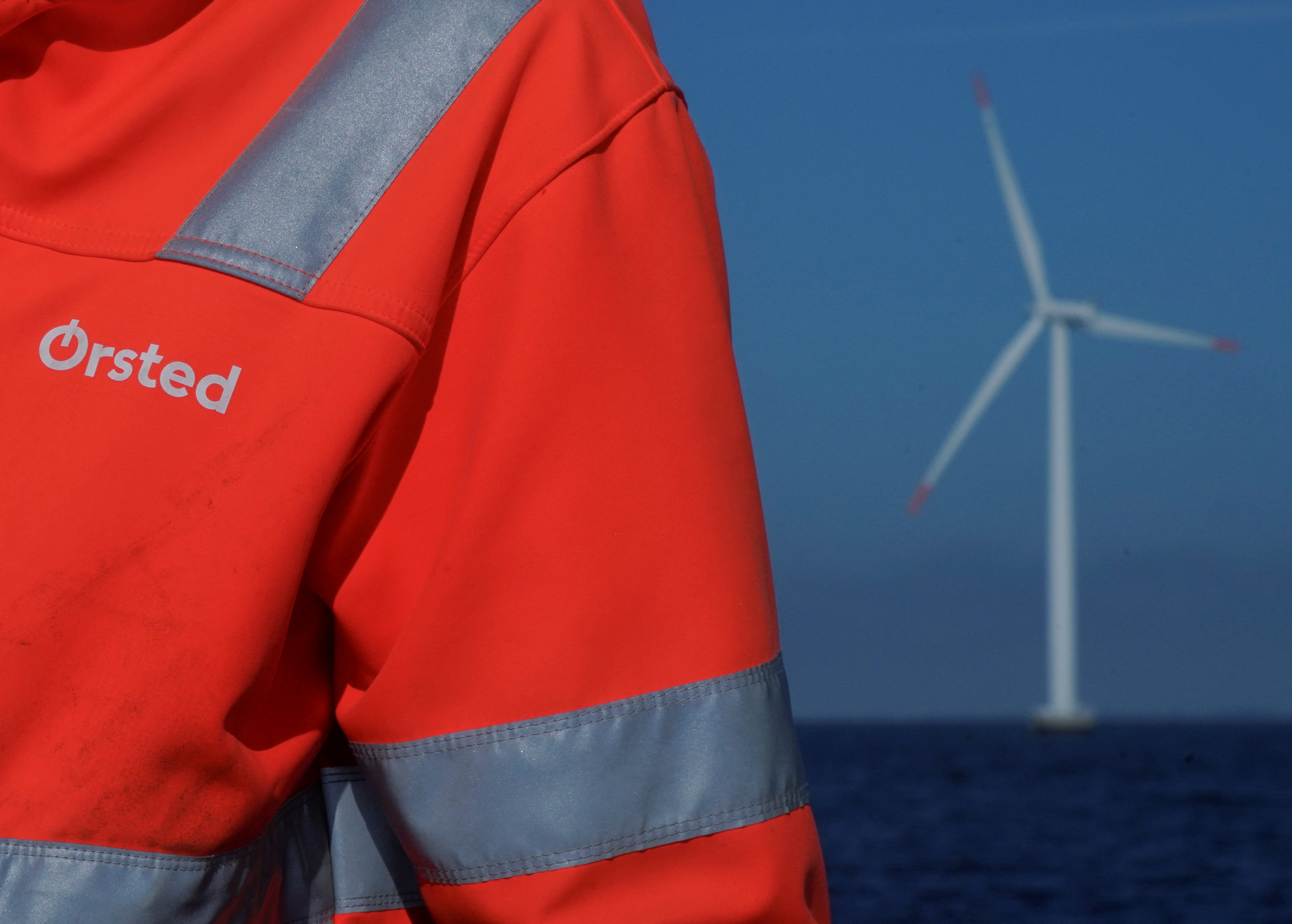 오르스테드 로고는 네스테드 근처 오르스테드 해상 풍력 발전소 직원이 입고 있는 재킷에서 볼 수 있습니다.