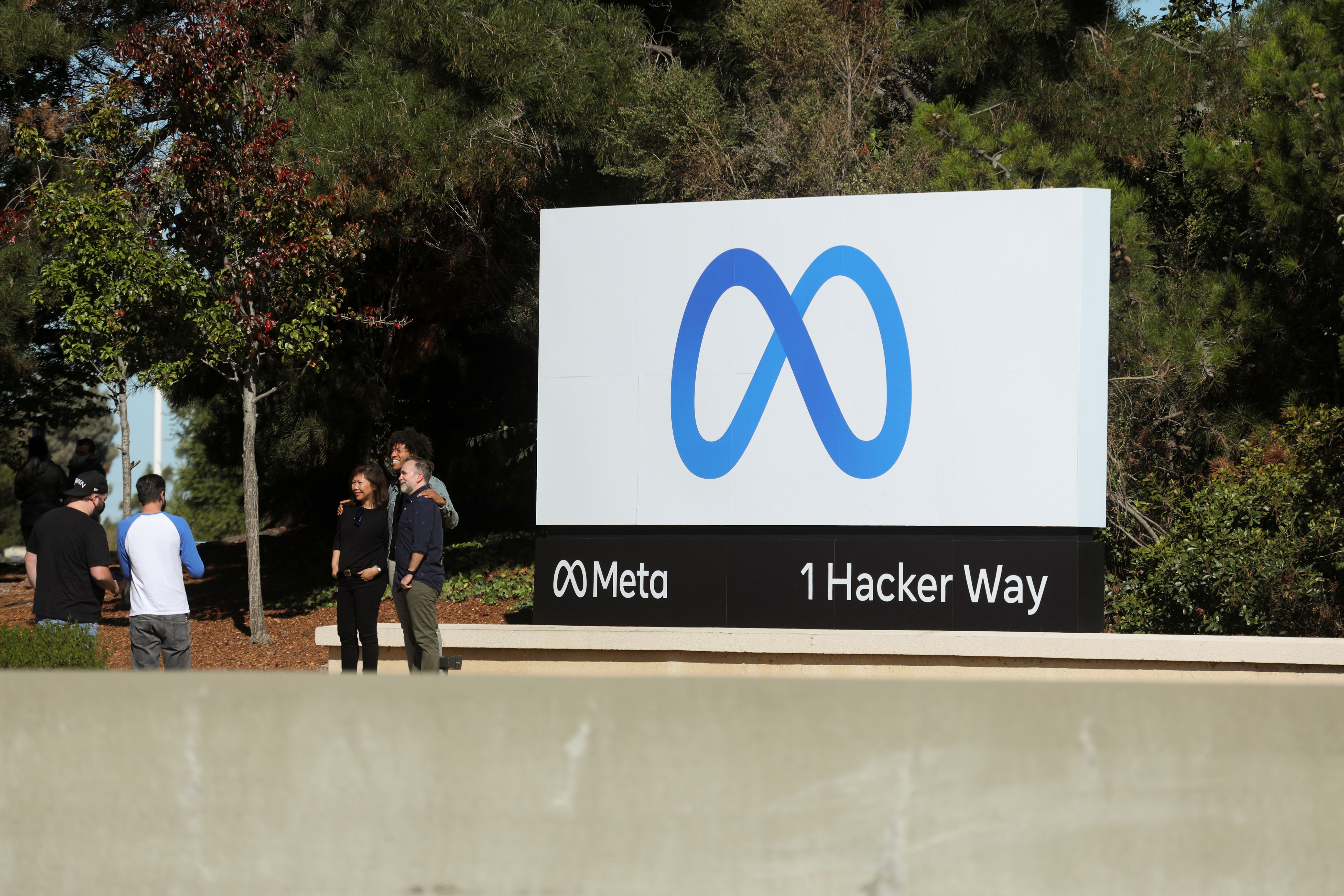 People pose for a photo in front of a sign of Meta, the new name for the company formerly known as Facebook, at its headquarters in Menlo Park, California, U.S. October 28, 2021. REUTERS/Nathan Frandino