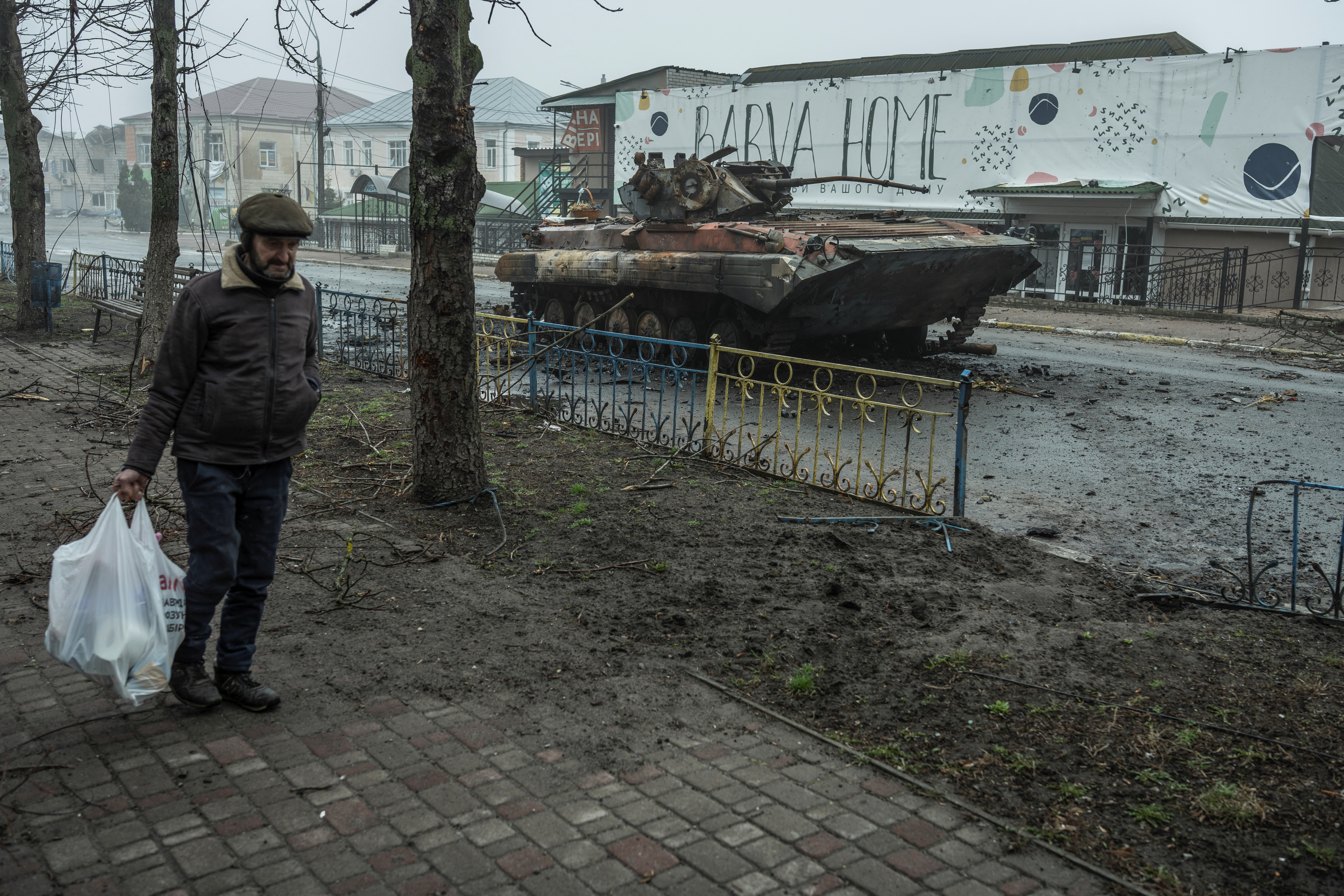 A local man walks past a damaged armoured personal carrier in the town of Makariv