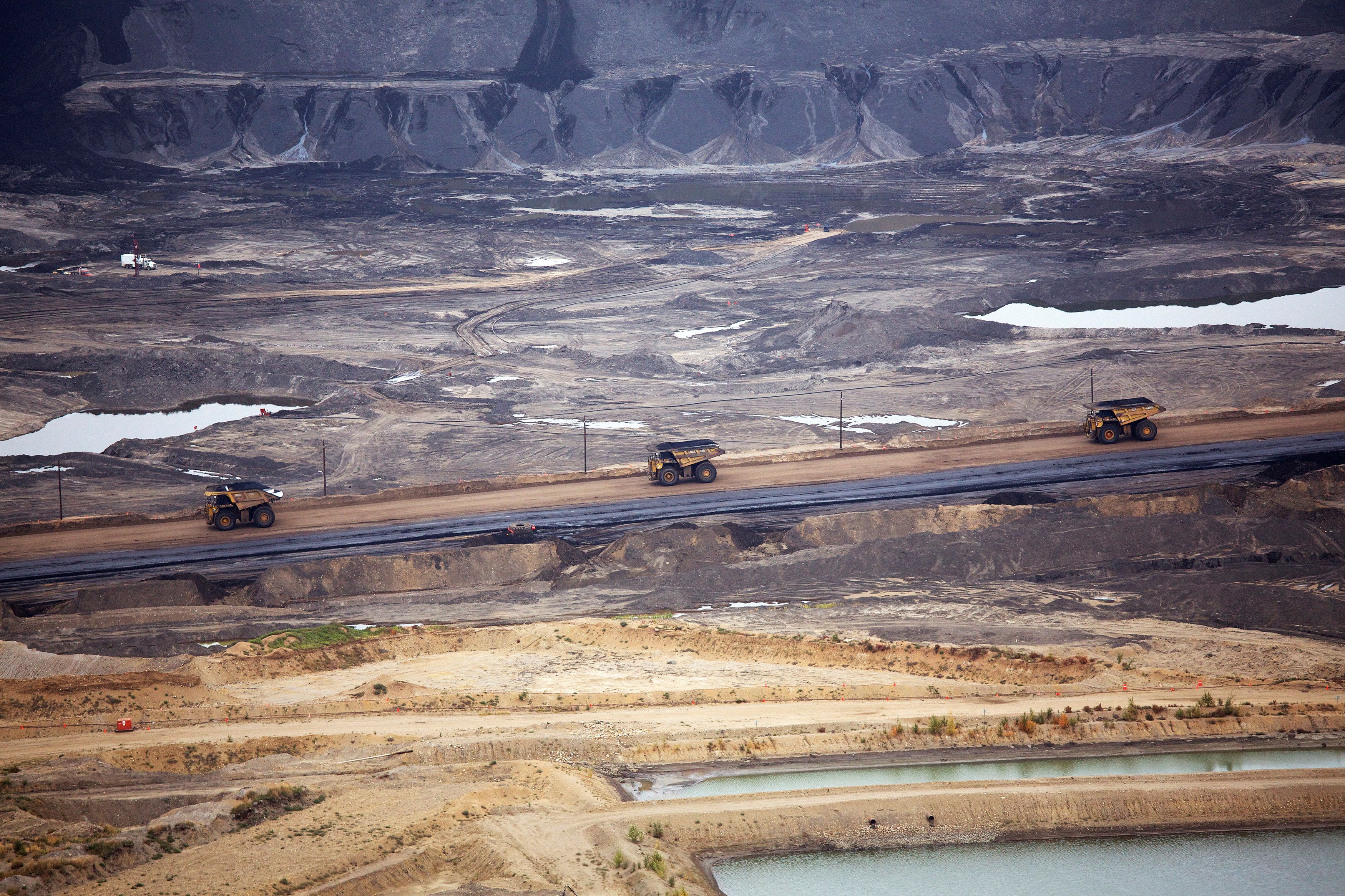 Giant dump trucks haul raw tar sands at the Syncrude tar sands operations near Fort McMurray.