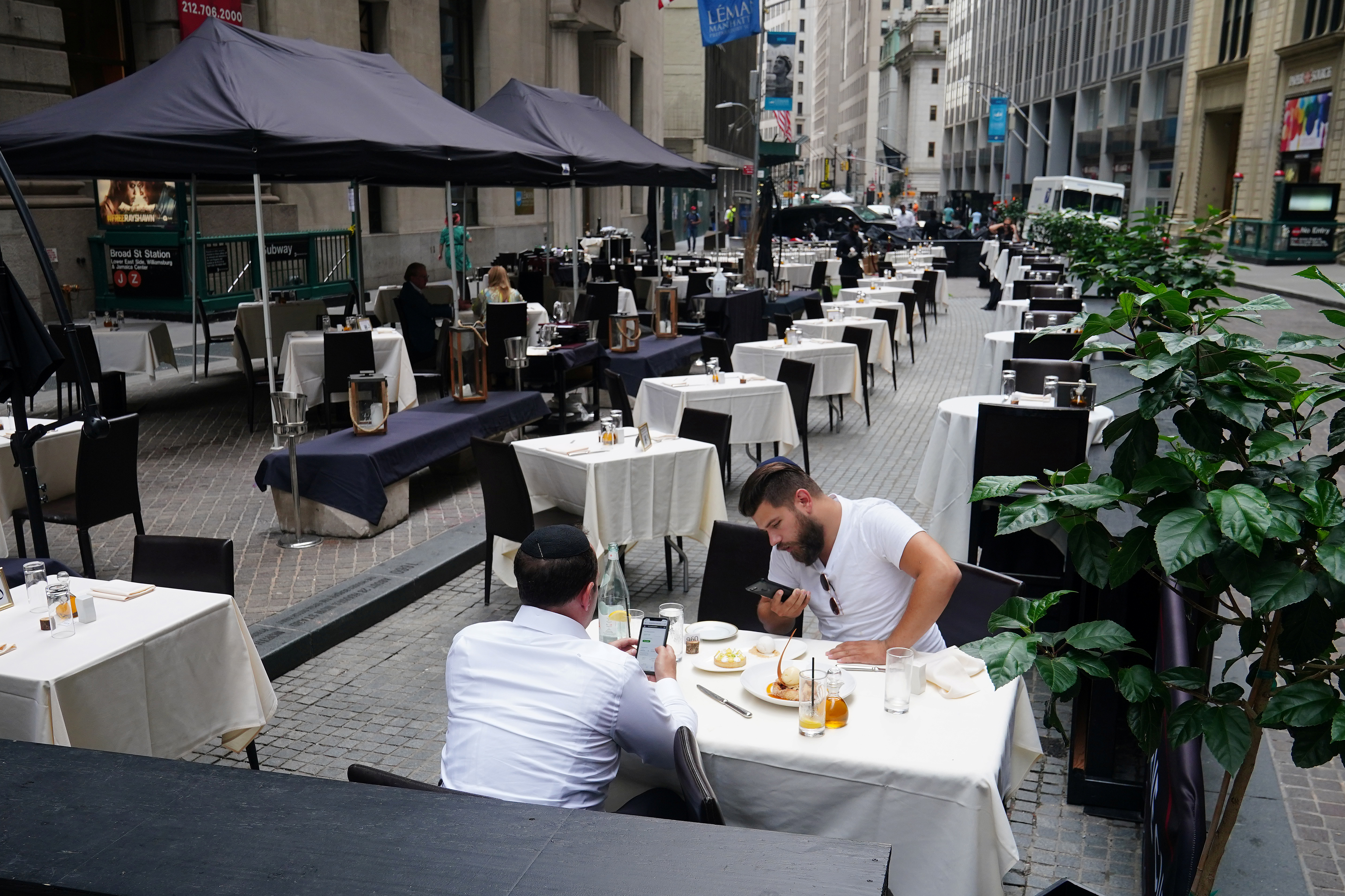 People eat at a mostly empty restaurant with tables on the street in the financial district