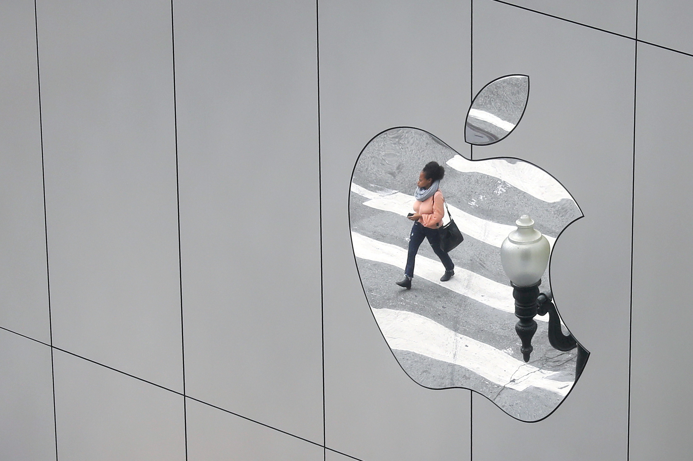 A woman is reflected in a Apple store logo in San Francisco