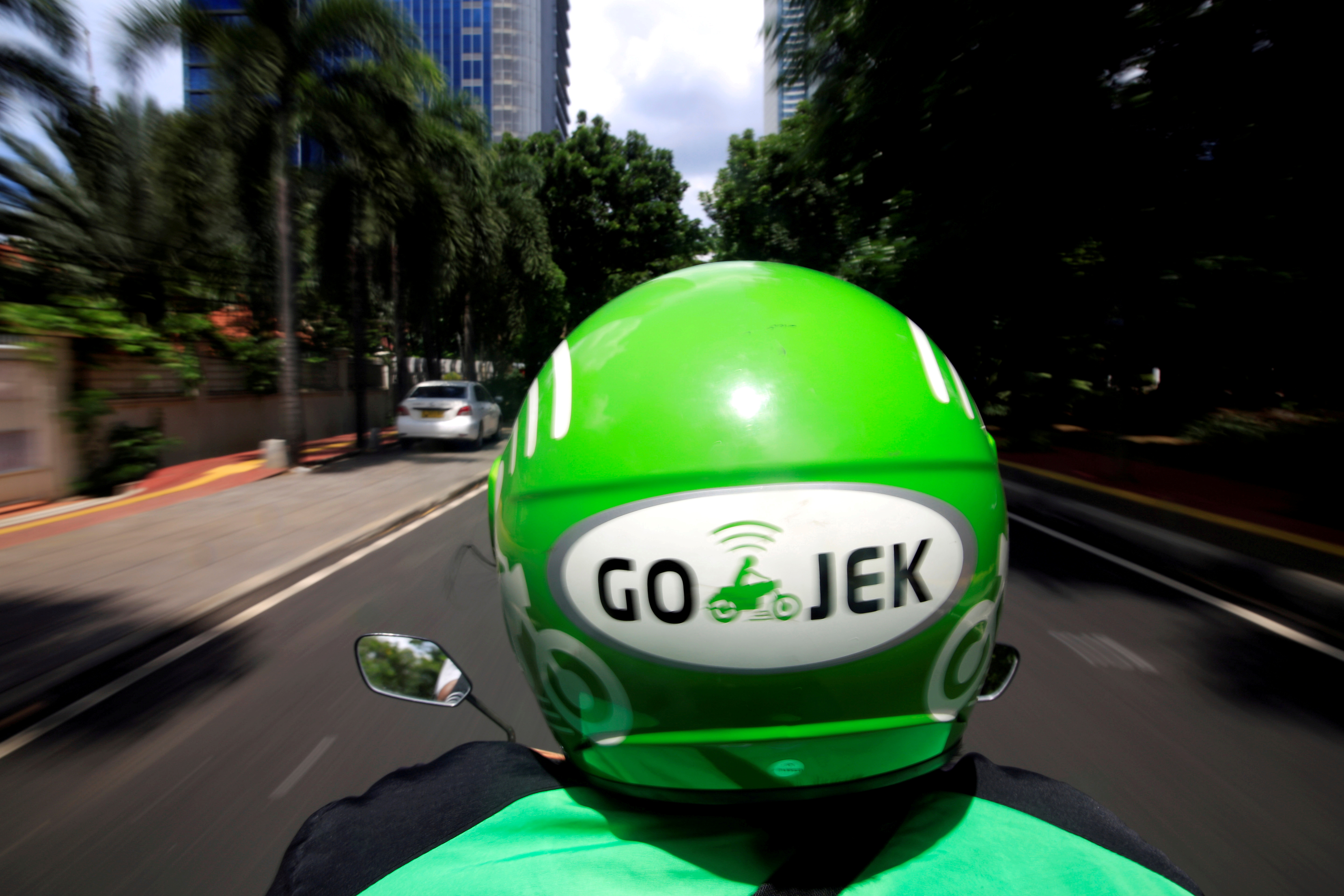 A Go-Jek driver rides a motorcycle on a street in Jakarta, Indonesia