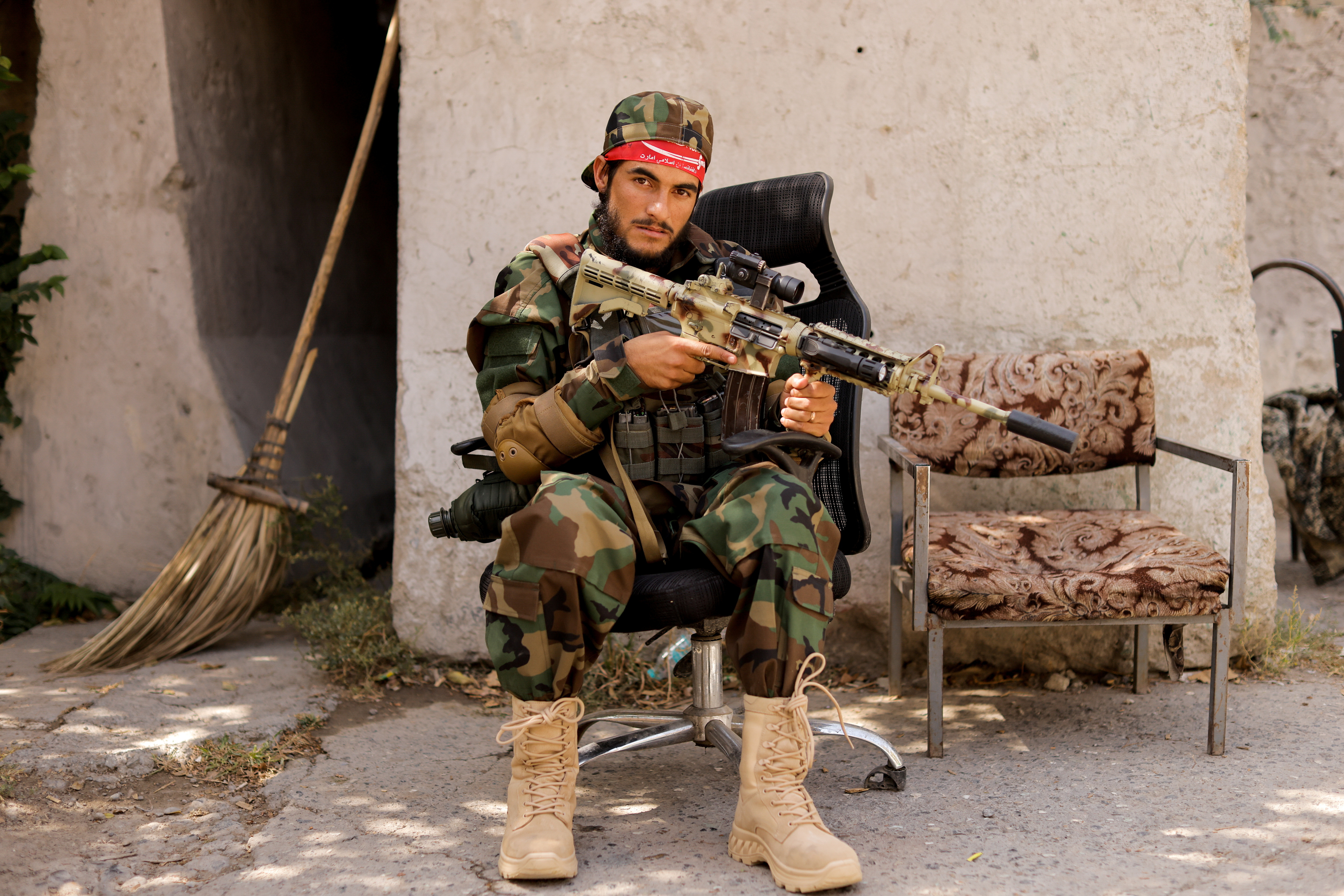 A Taliban soldier sits outside a news conference where Taliban officials announced they will start issuing passports