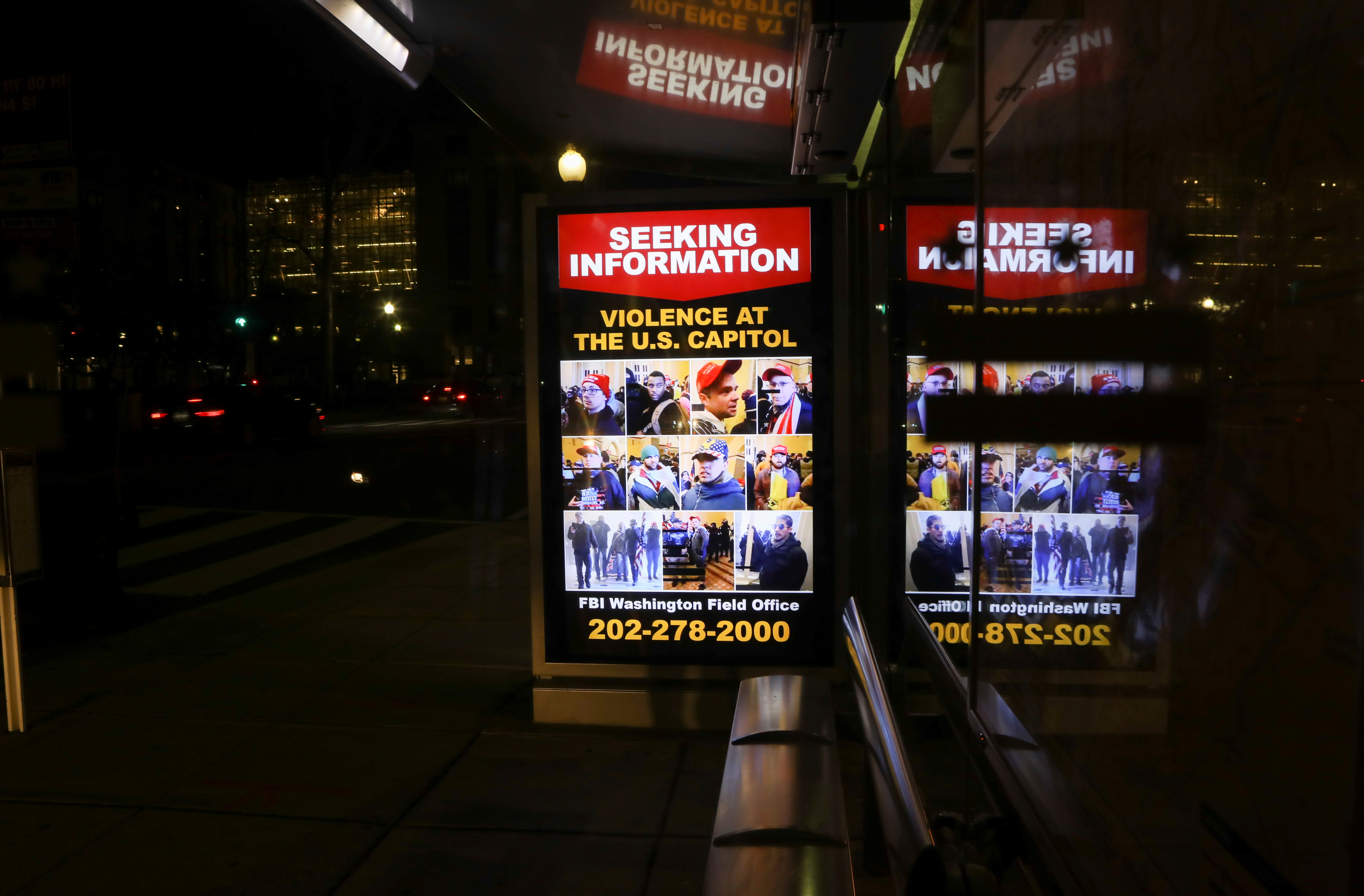 A sign at a bus stop shows people wanted by law enforcement, three days after a protest of the U.S. Congress certification of the November election results the 2020 election in Washington